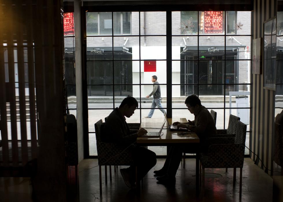 Two employees work on their computers at a Beijing coffee house