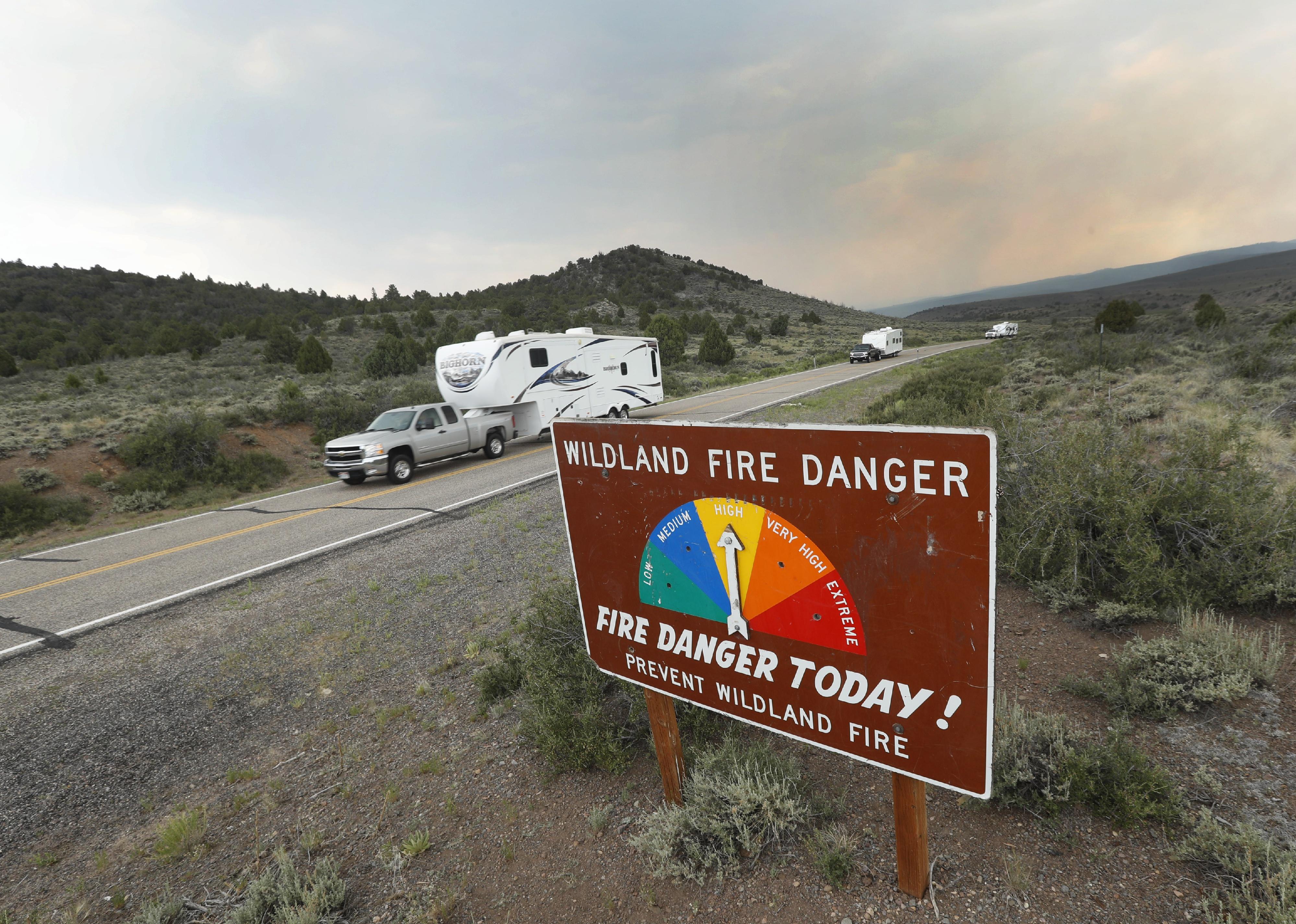 People move travel trailers down Highway 143 from their homes that have been evacuated due to a wildfire.