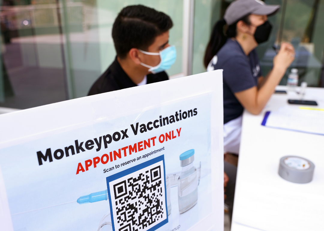 Health workers sitting at a check-in table at a pop-up Monkeypox vaccination clinic.