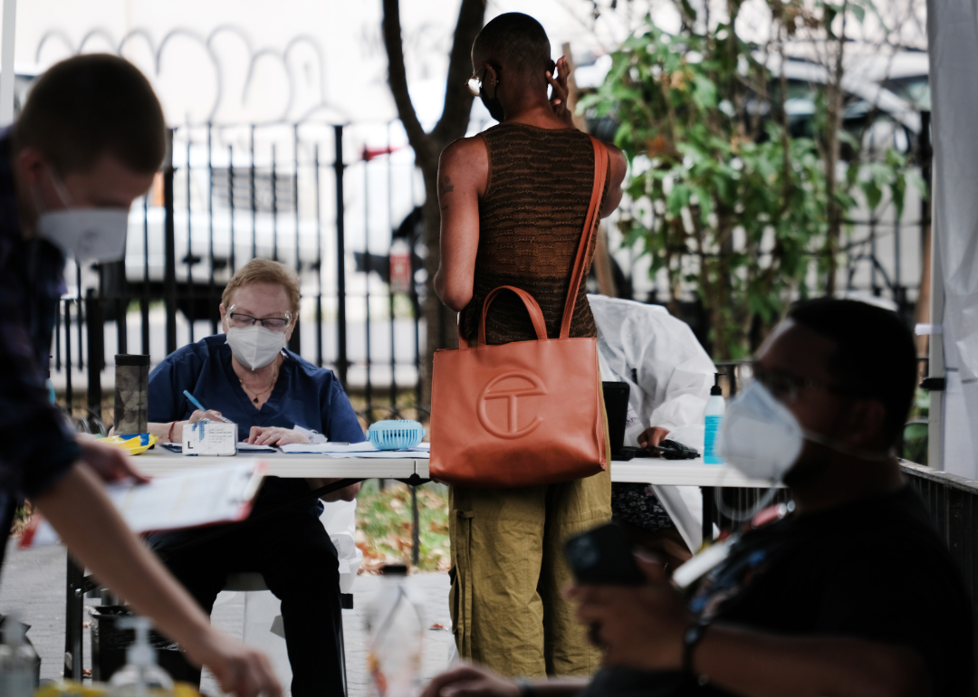 A person stands at a sign in table for the vaccine.