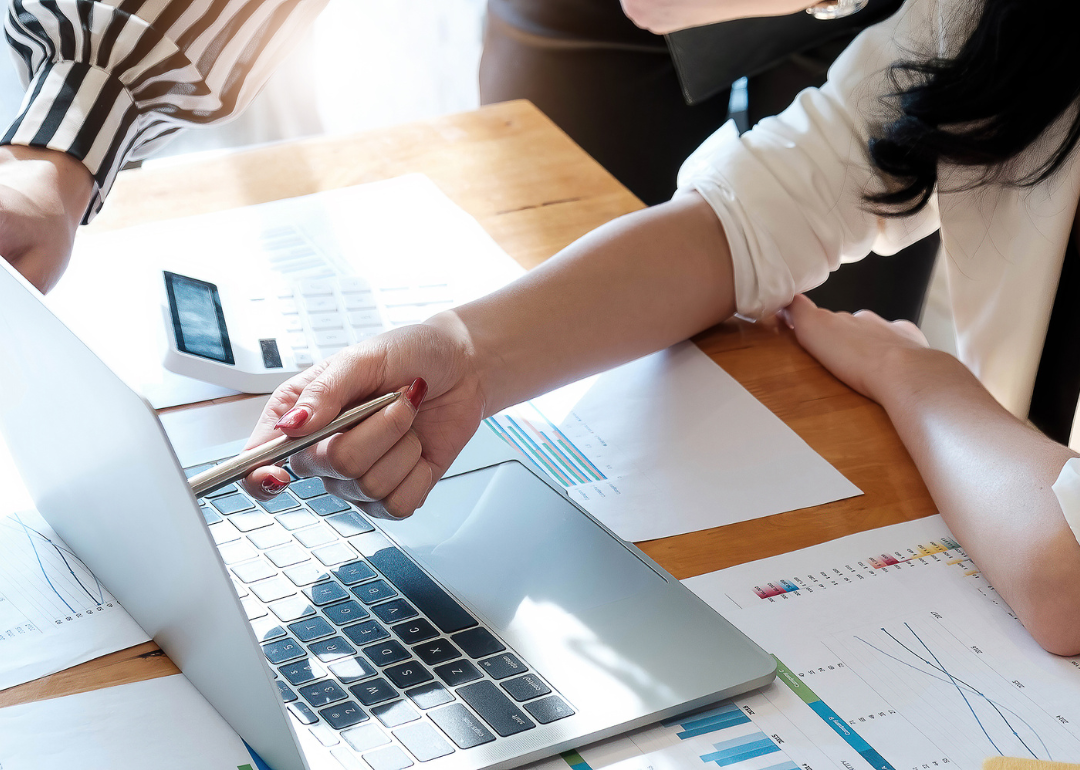 Two people discuss financial documents on a laptop.