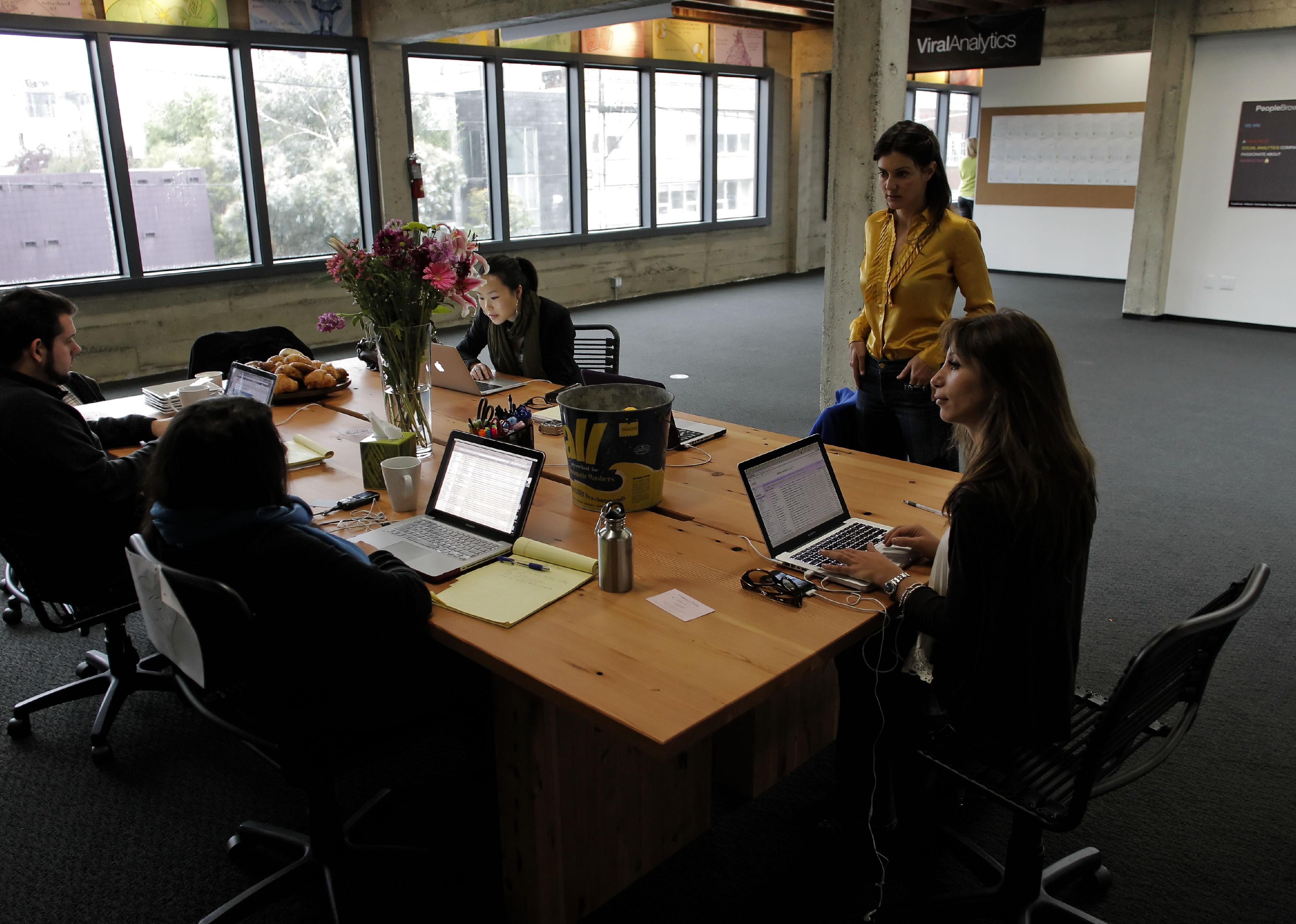 A group of people sitting at a table working on their laptops.