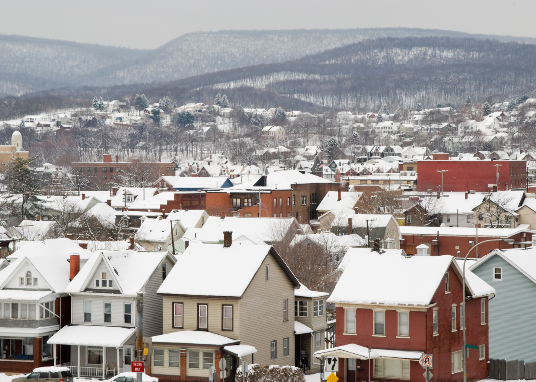 Rooftops covered in snow, surrounded by mountains.