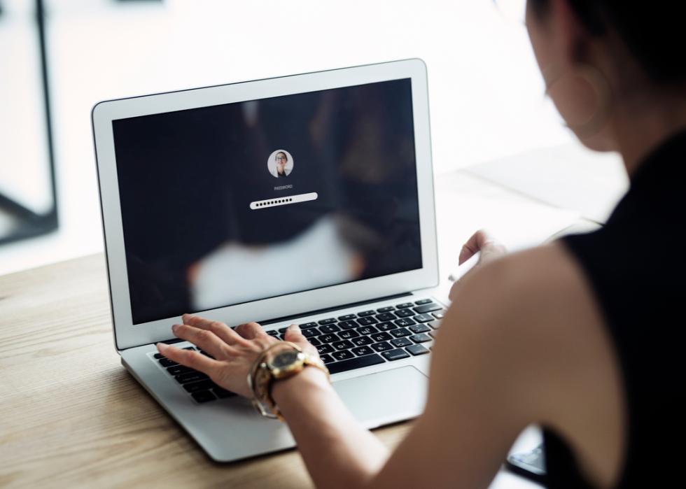 A woman logging into her computer with a password.