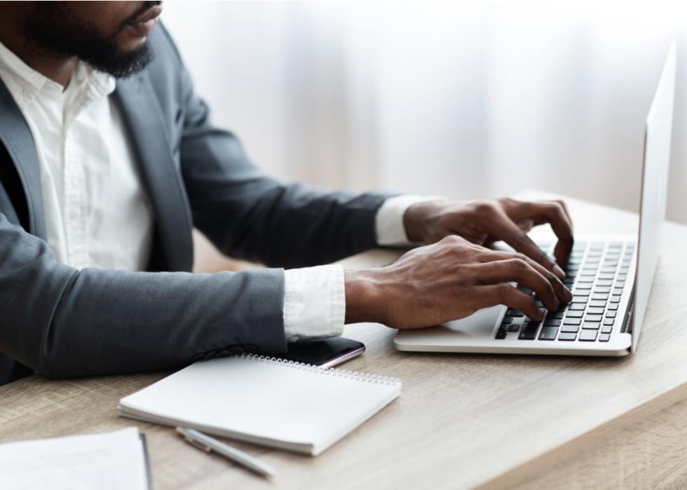 Man in a suit typing on a keyboard.