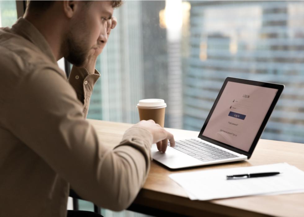 Young man logging into computer in office.