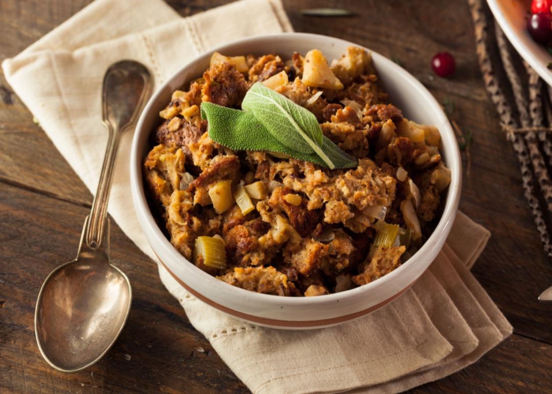 A white bowl of stuffing with celery and sage on top.