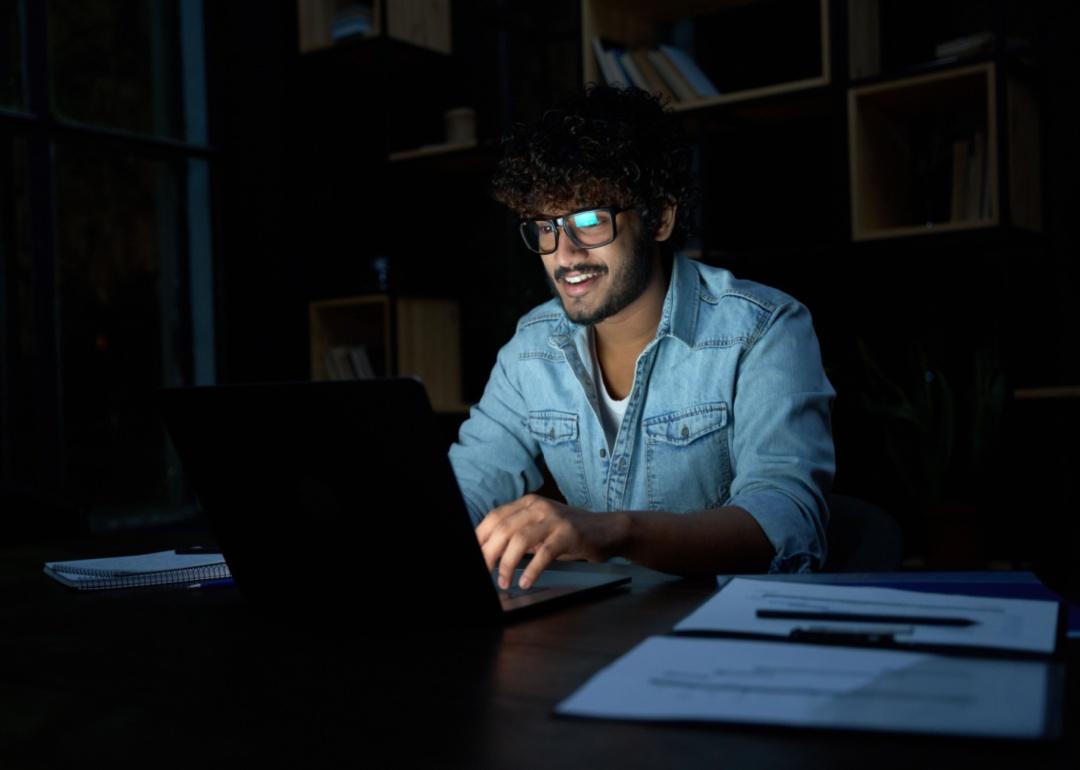 A person working on his laptop in the dark.