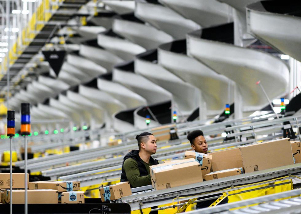 Employees moving boxes inside an Amazon fulfillment center.
