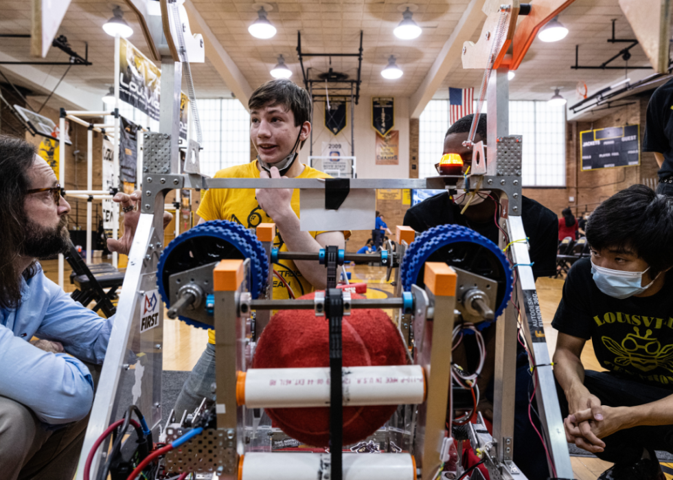Members of the Central High School robotics club gather around a robot canine.