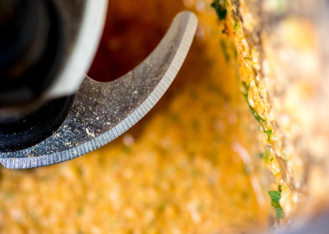 A close-up of a blade inside a food processor while making a sauce.