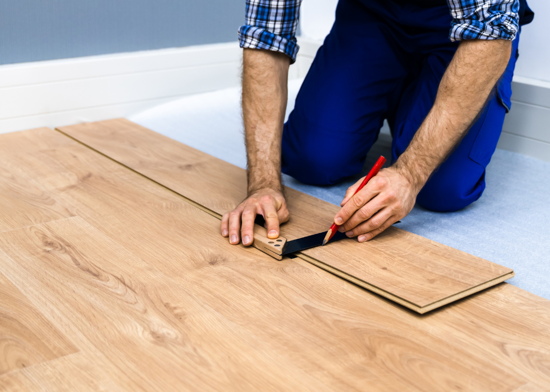 Person lining up and installing laminate flooring.