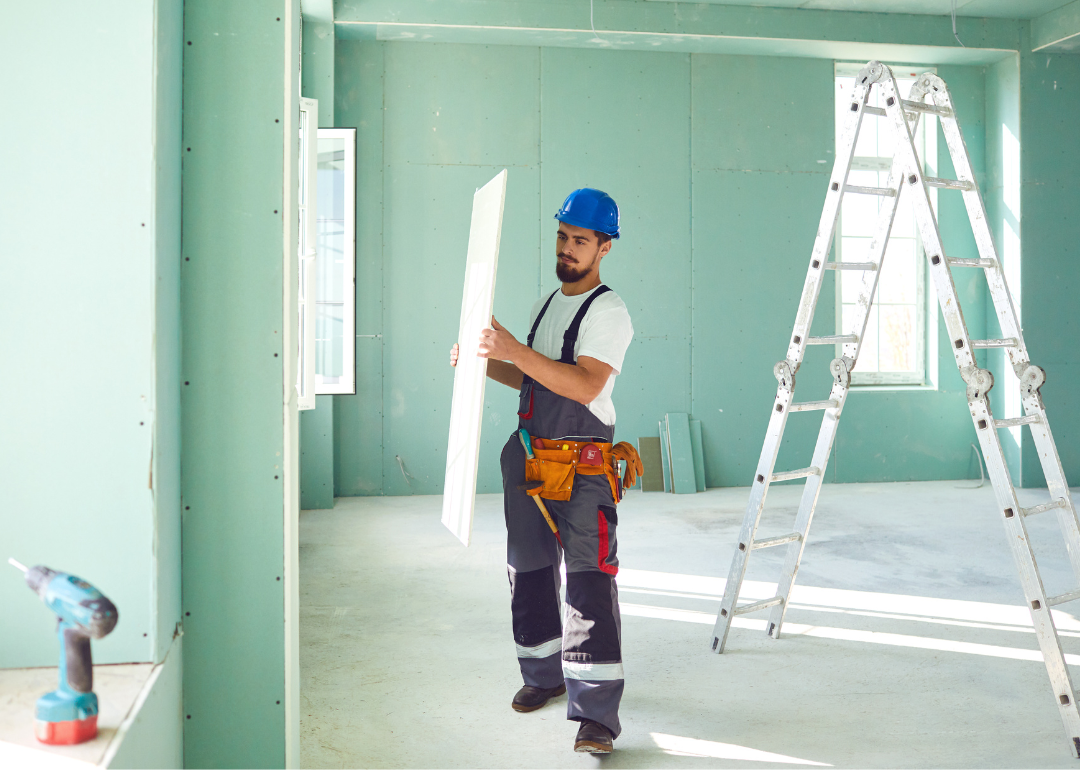 Person carrying plasterboard to install.