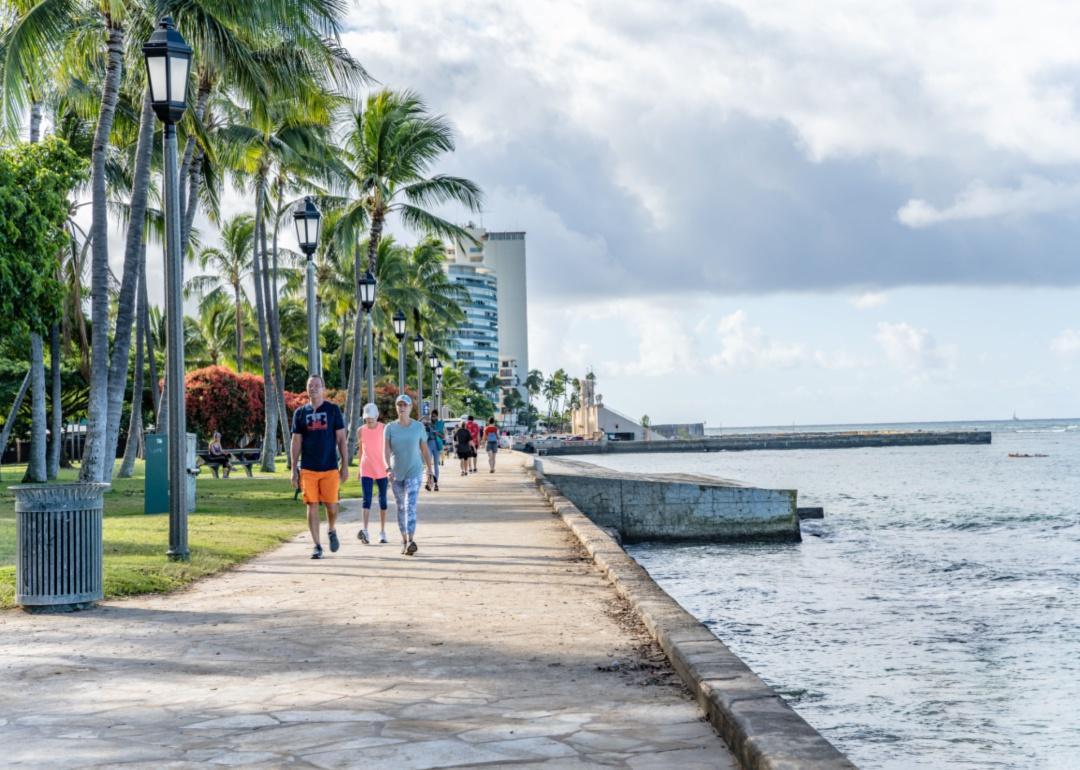 People walking along the boardwalk on the water.