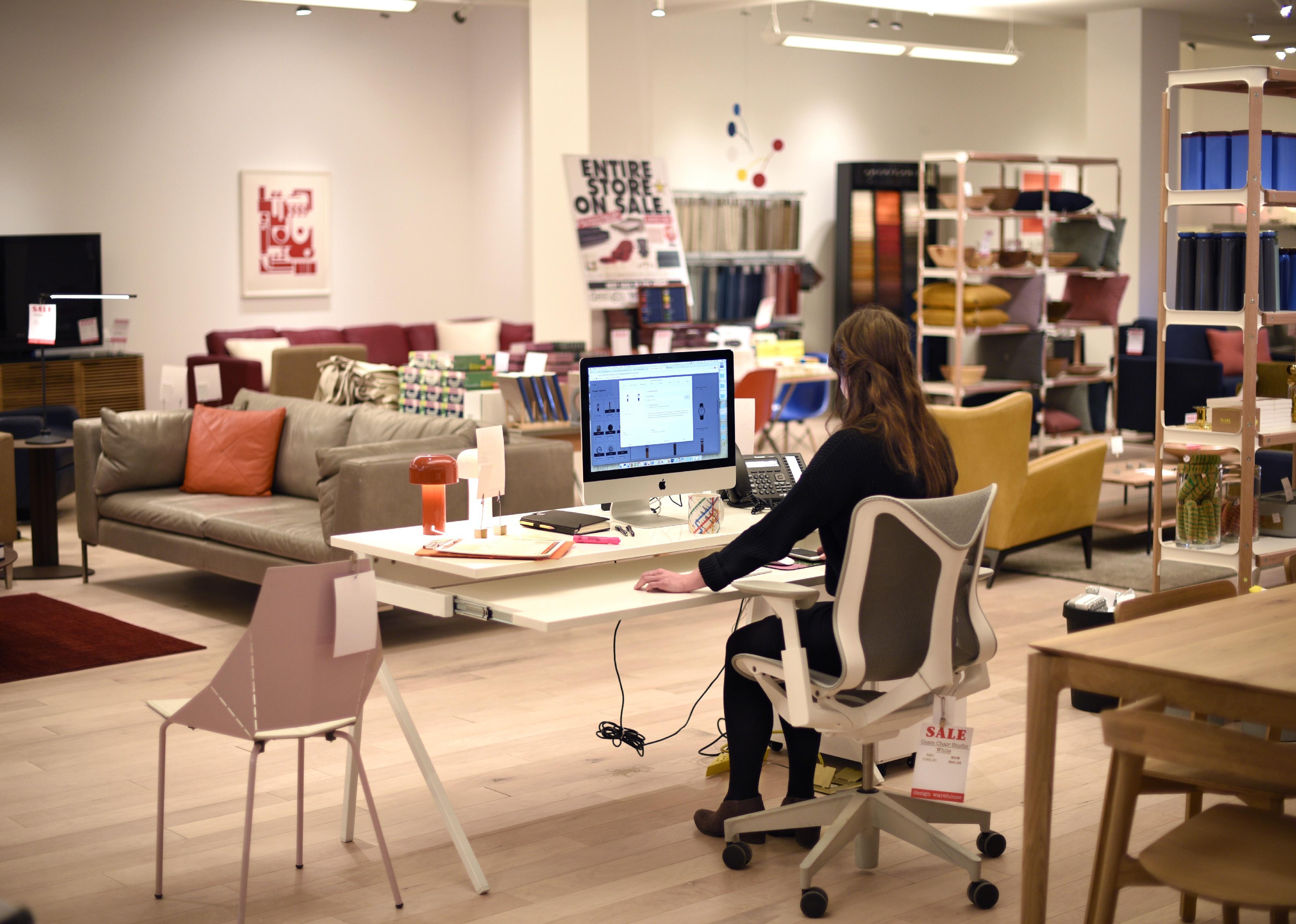An employee works at her computer in a home and office furniture and accessory store