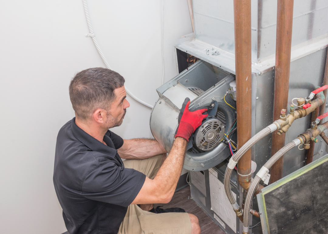 A technician works on a furnace blower fan.