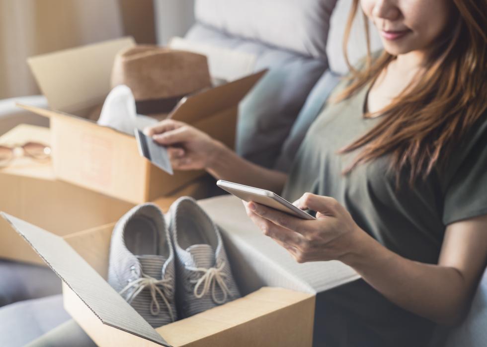 Woman with shipping box with shoes, phone, and credit card