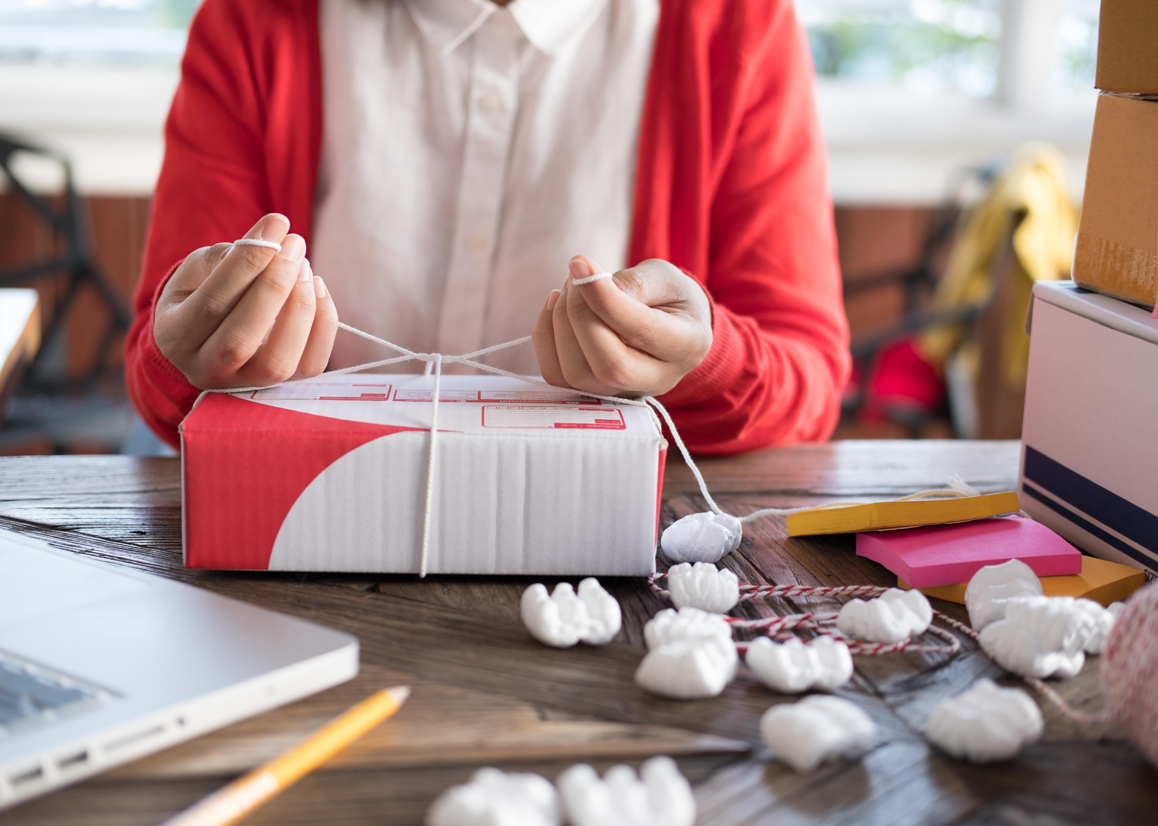 Small business owner packing cardboard box at workplace.