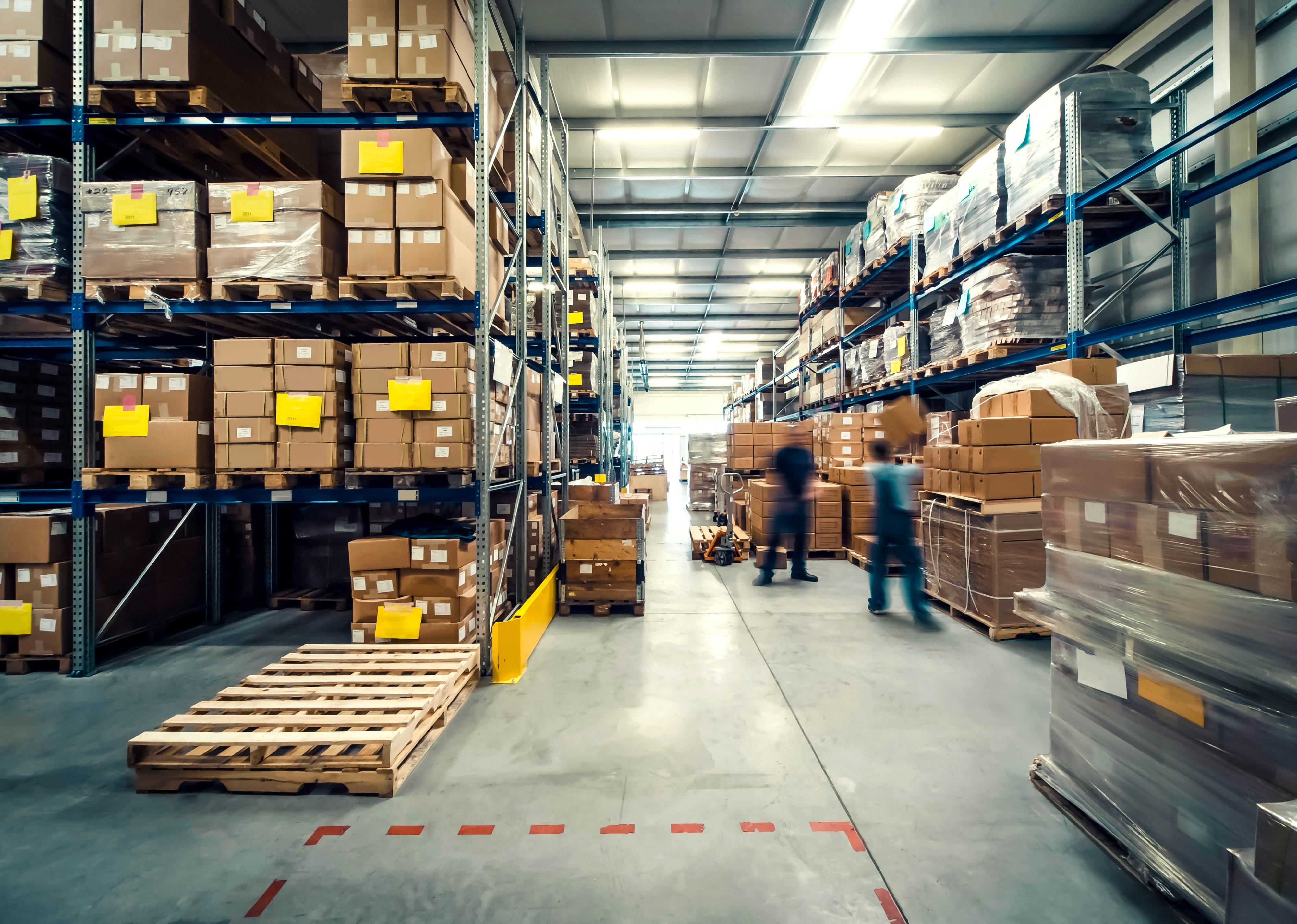 Warehouse interior with shelves, pallets, and boxes.