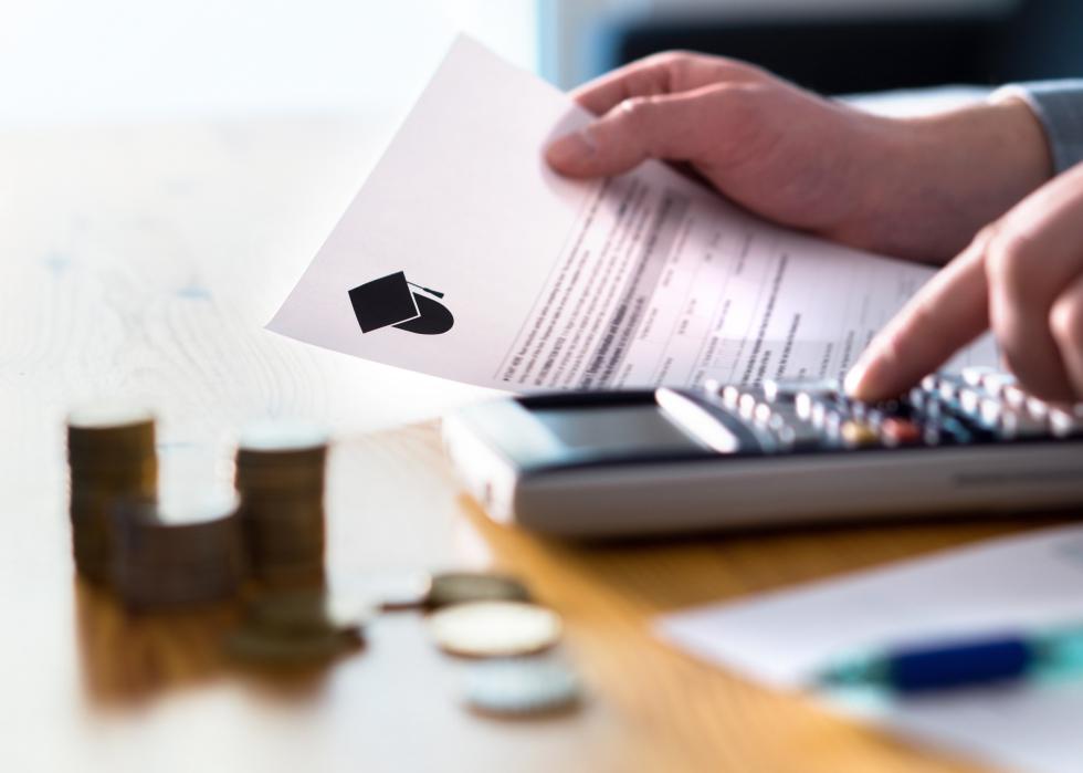 Close-up of man using calculator and holding paper