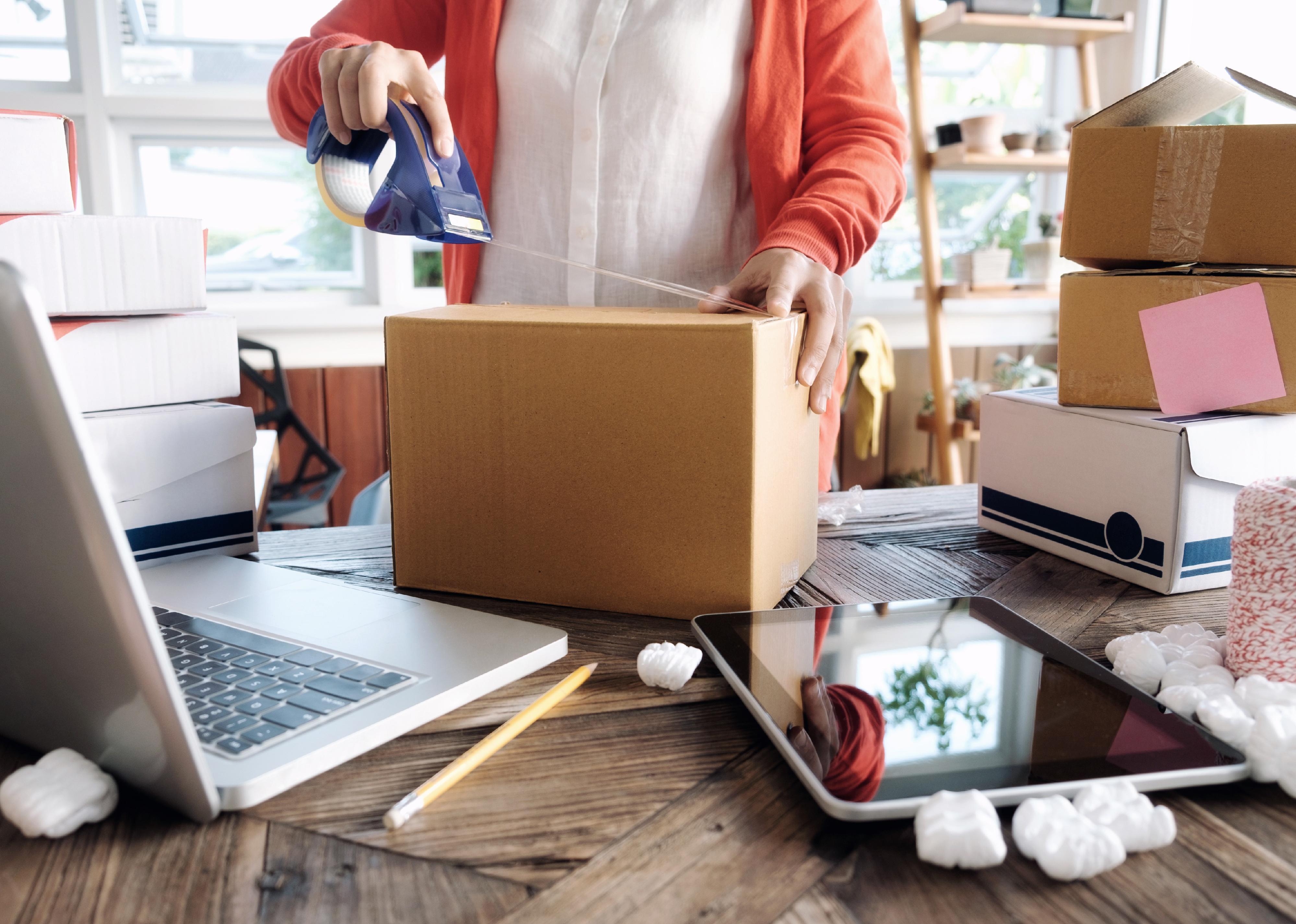 Online business owner packing box for shipment.