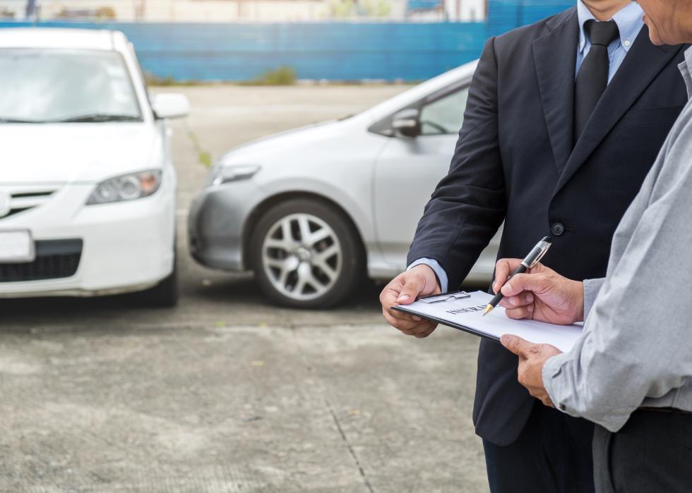 Insurance agent, customer, and a damaged car 