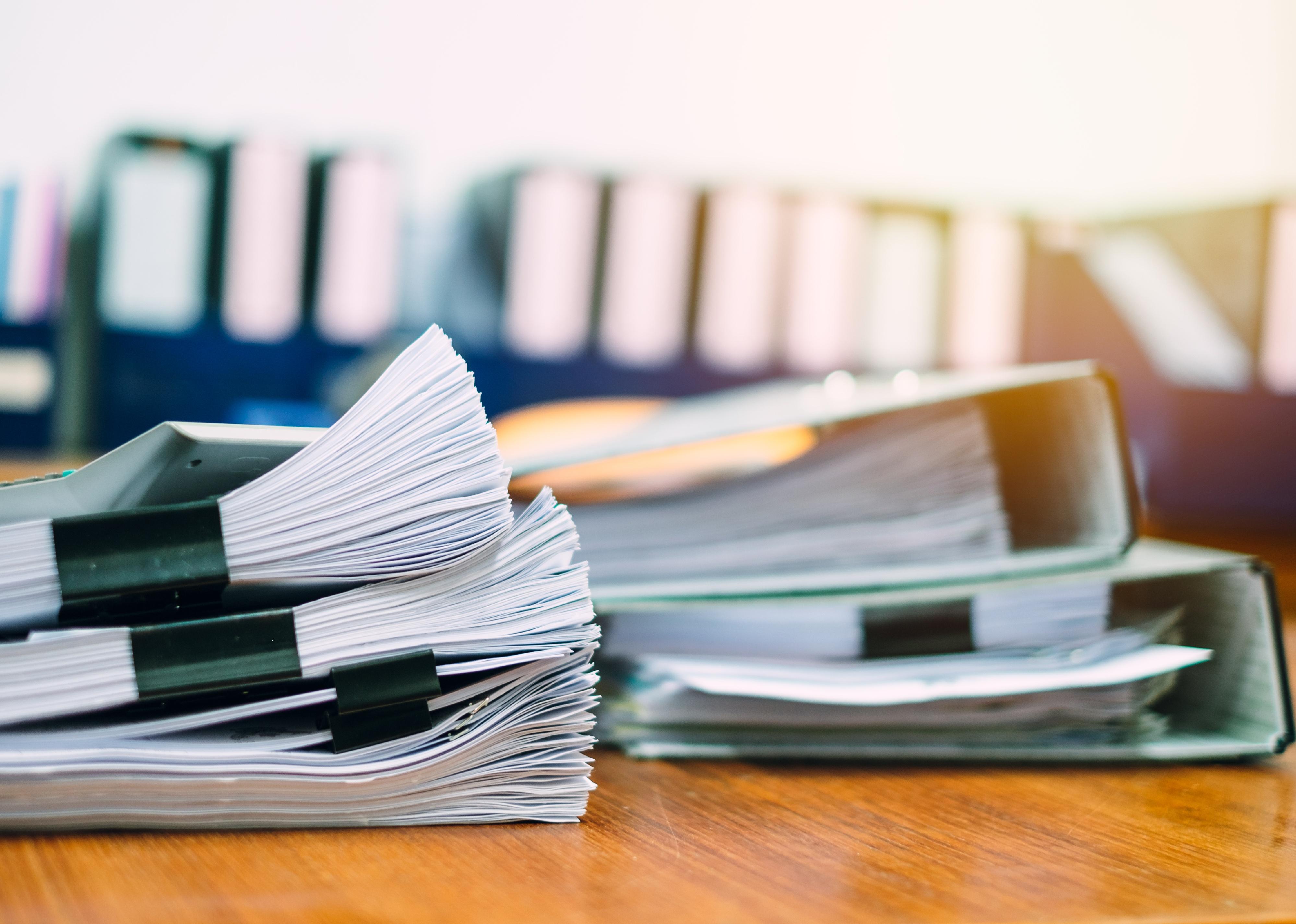 Stack of business papers on modern white office desk.