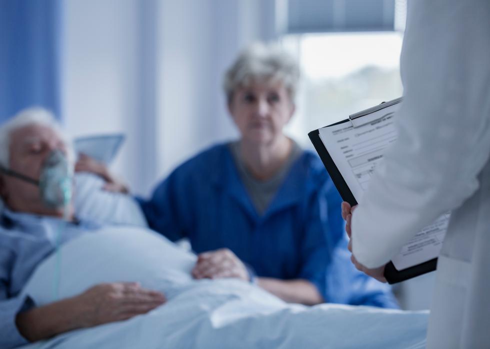 Doctor presenting results to a patient with an oxygen mask and his wife.