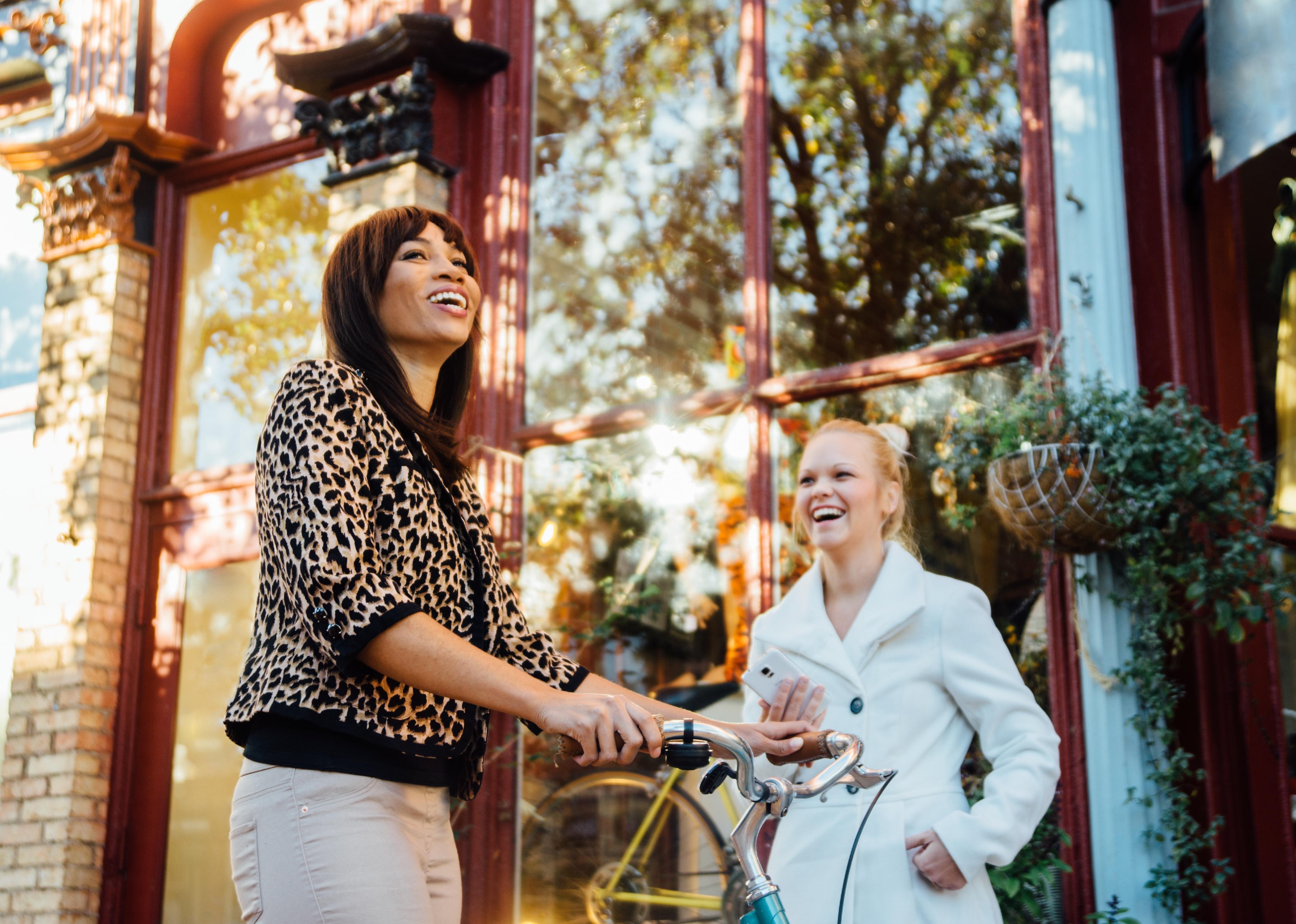 Two woman in small town downtown laughing.