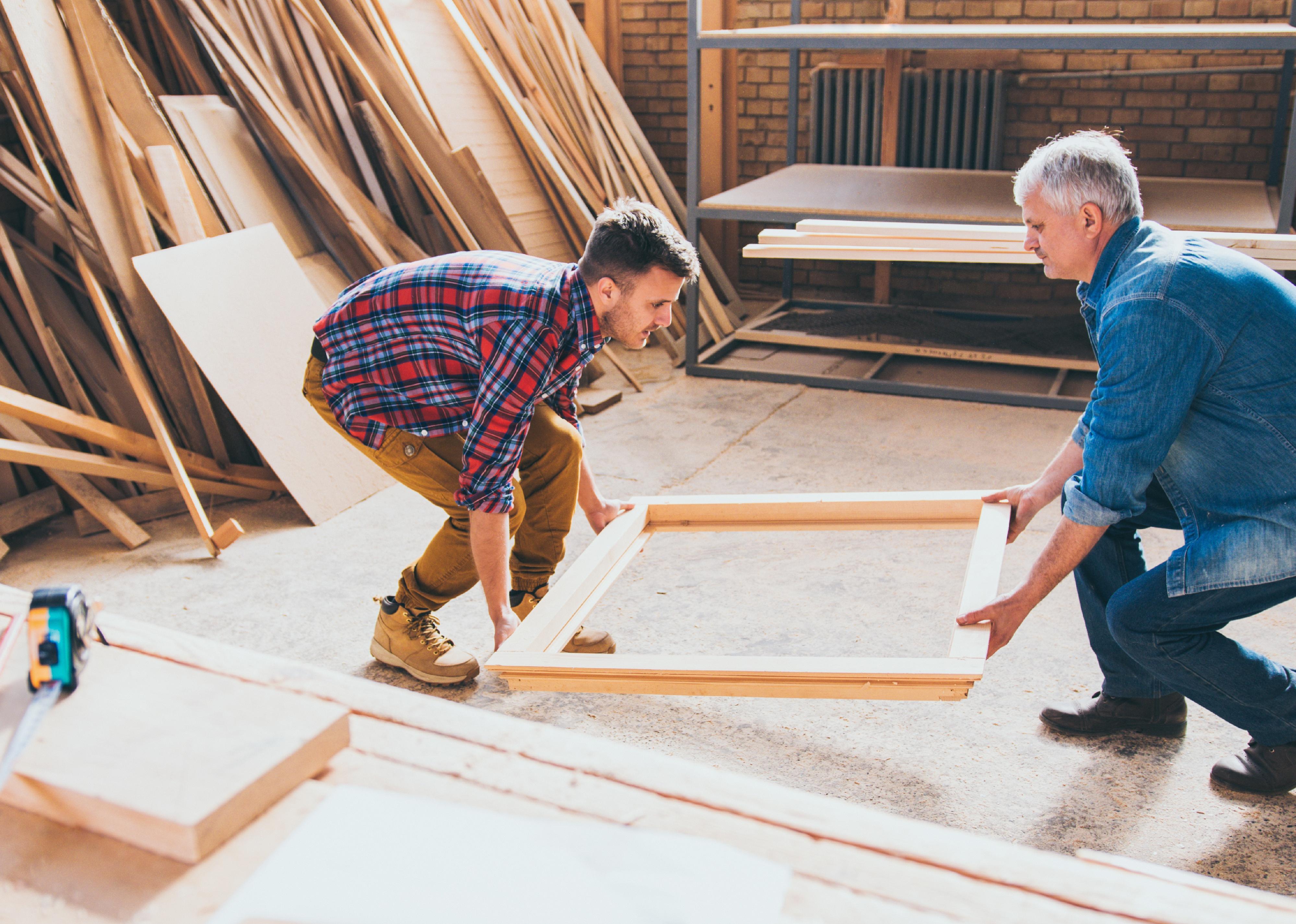 Carpenters lifting window frame.