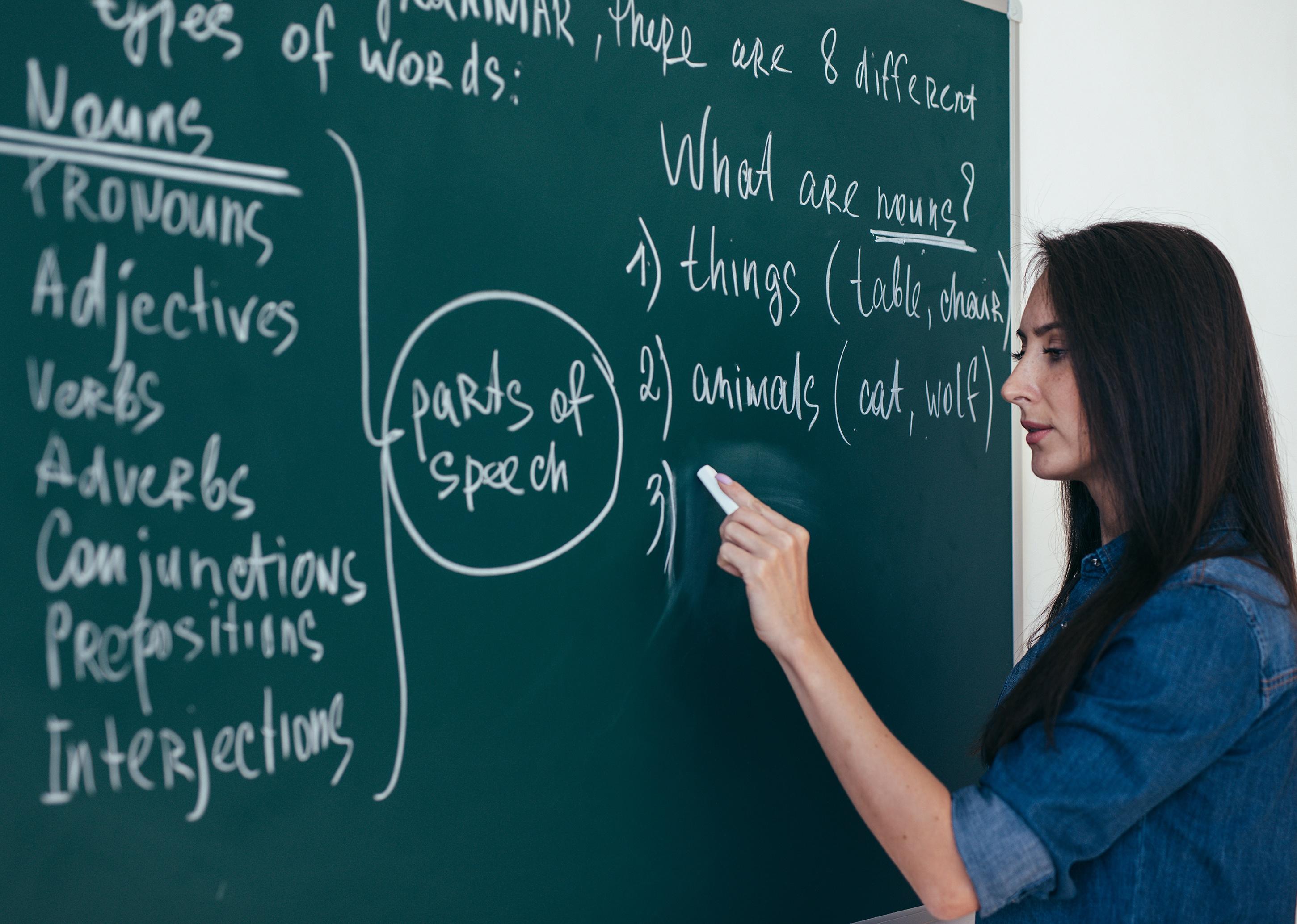 Teacher writing on blackboard in classroom