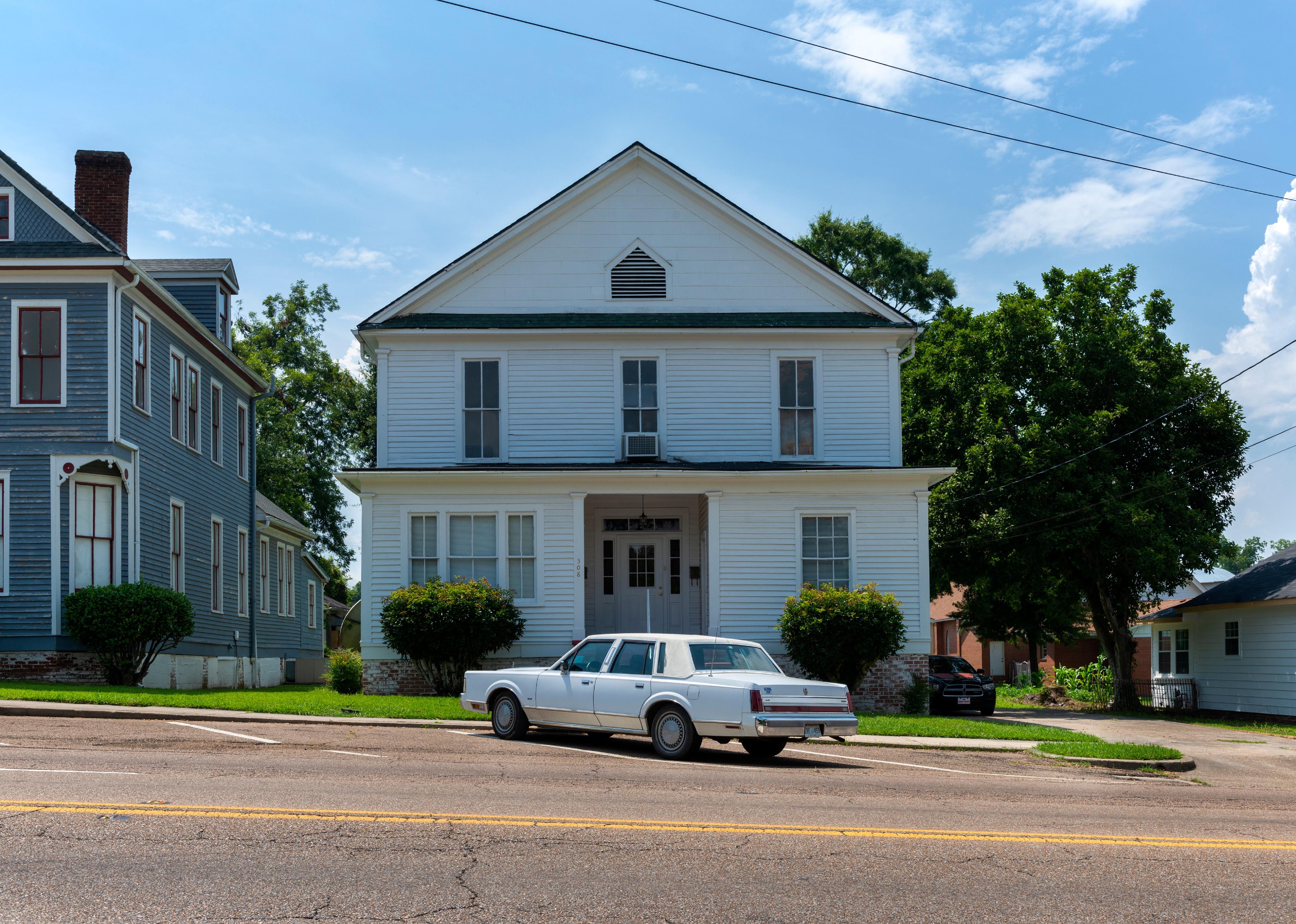 Vintage car parkerd in front of a wood house in the city of Vicksburg.