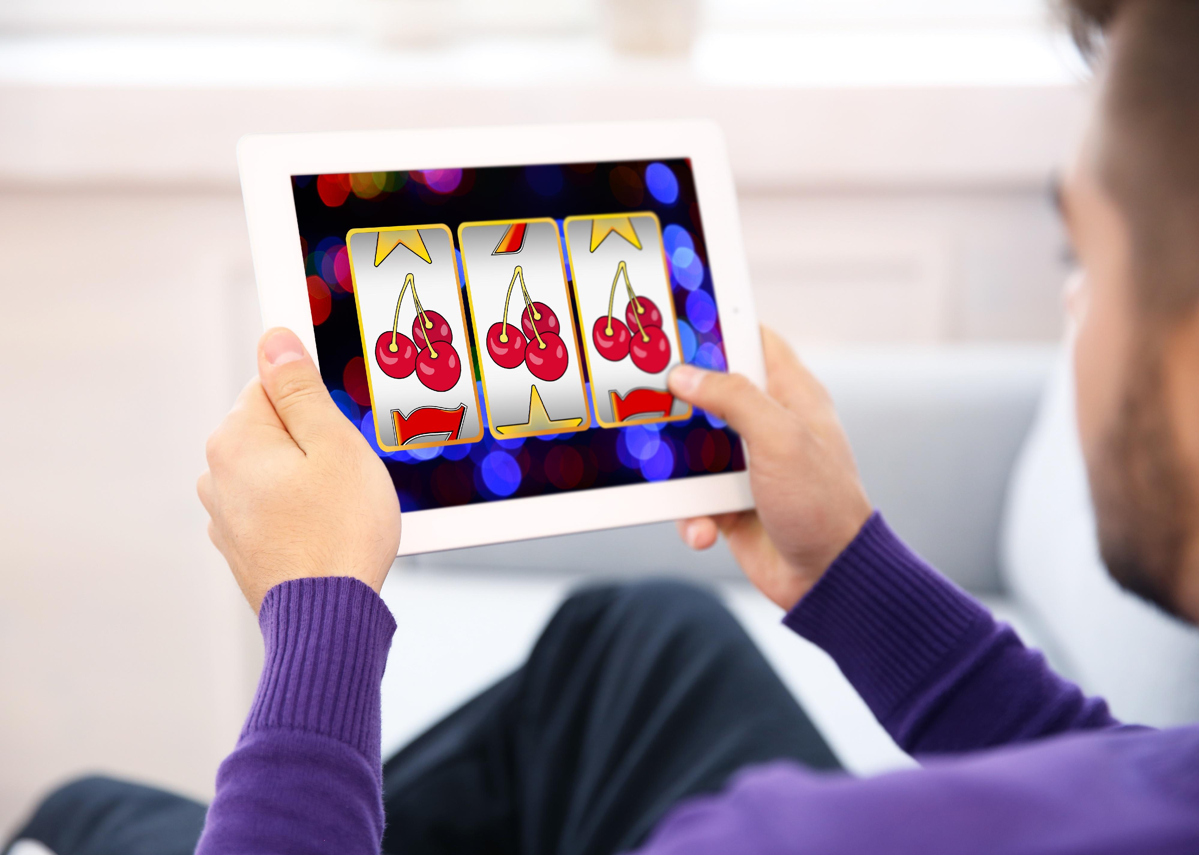 Man using tablet for playing slots  at home.