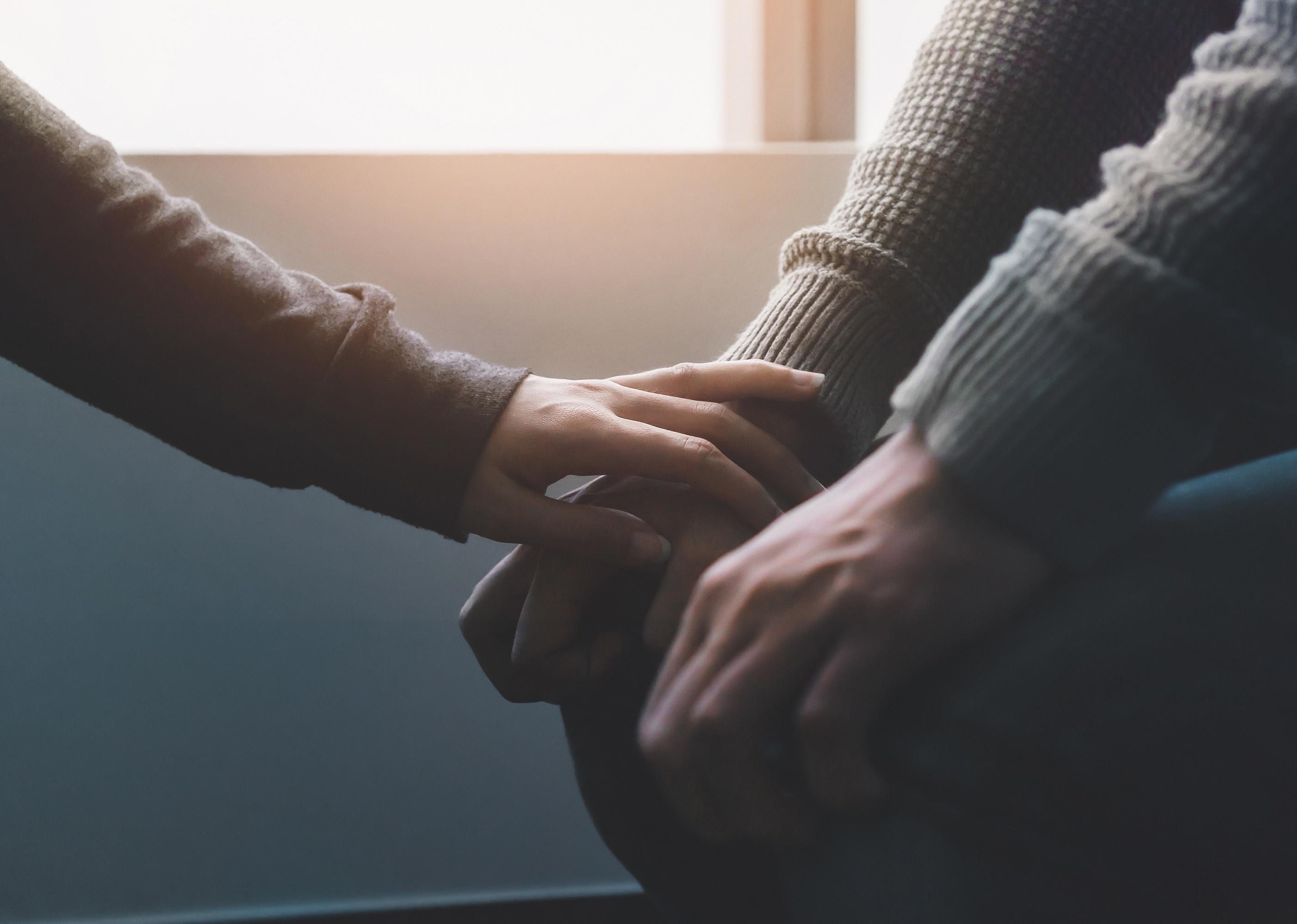 Close up of a hand touching another supportively.