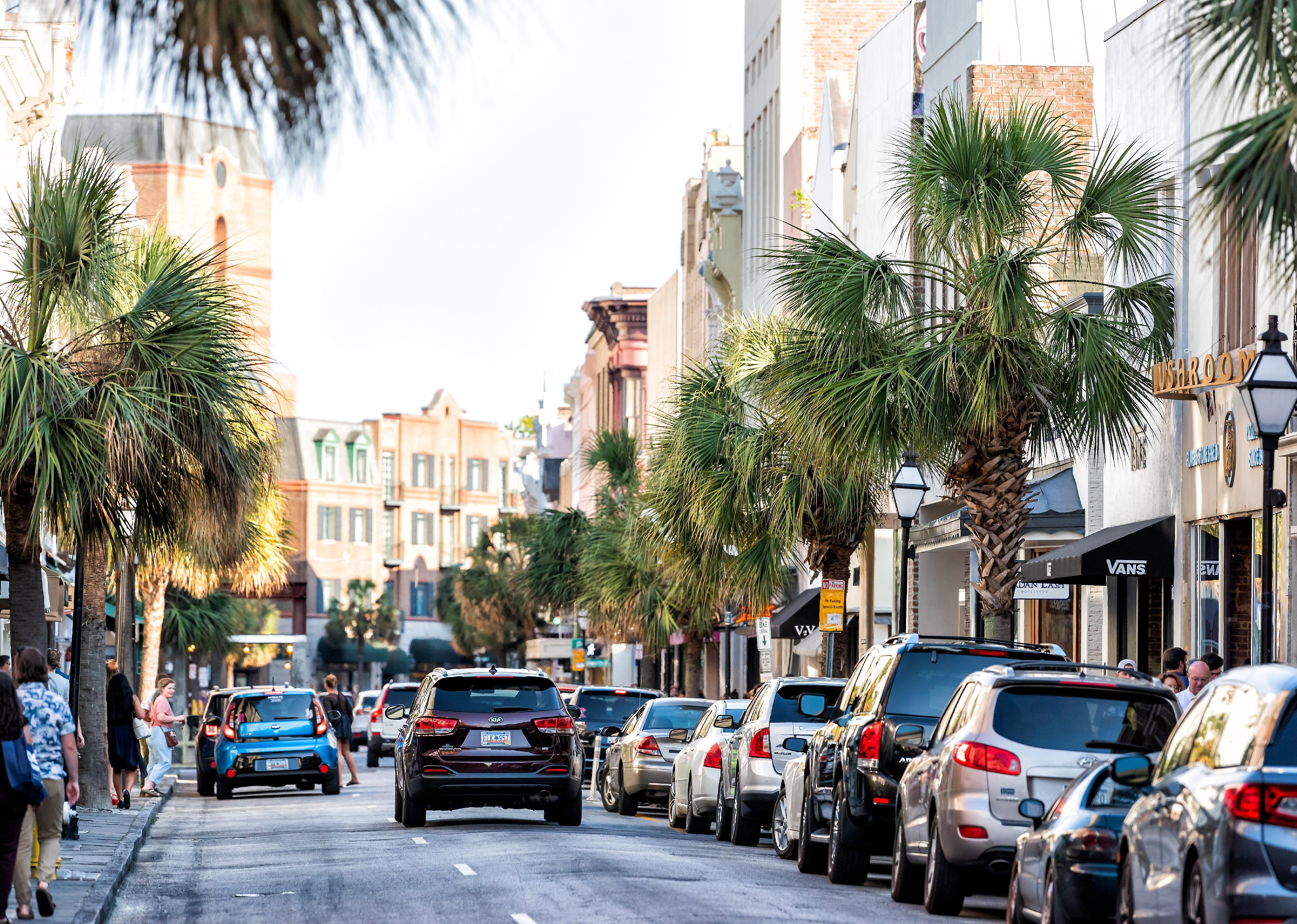 Downtown with people walking and cars parked on road.