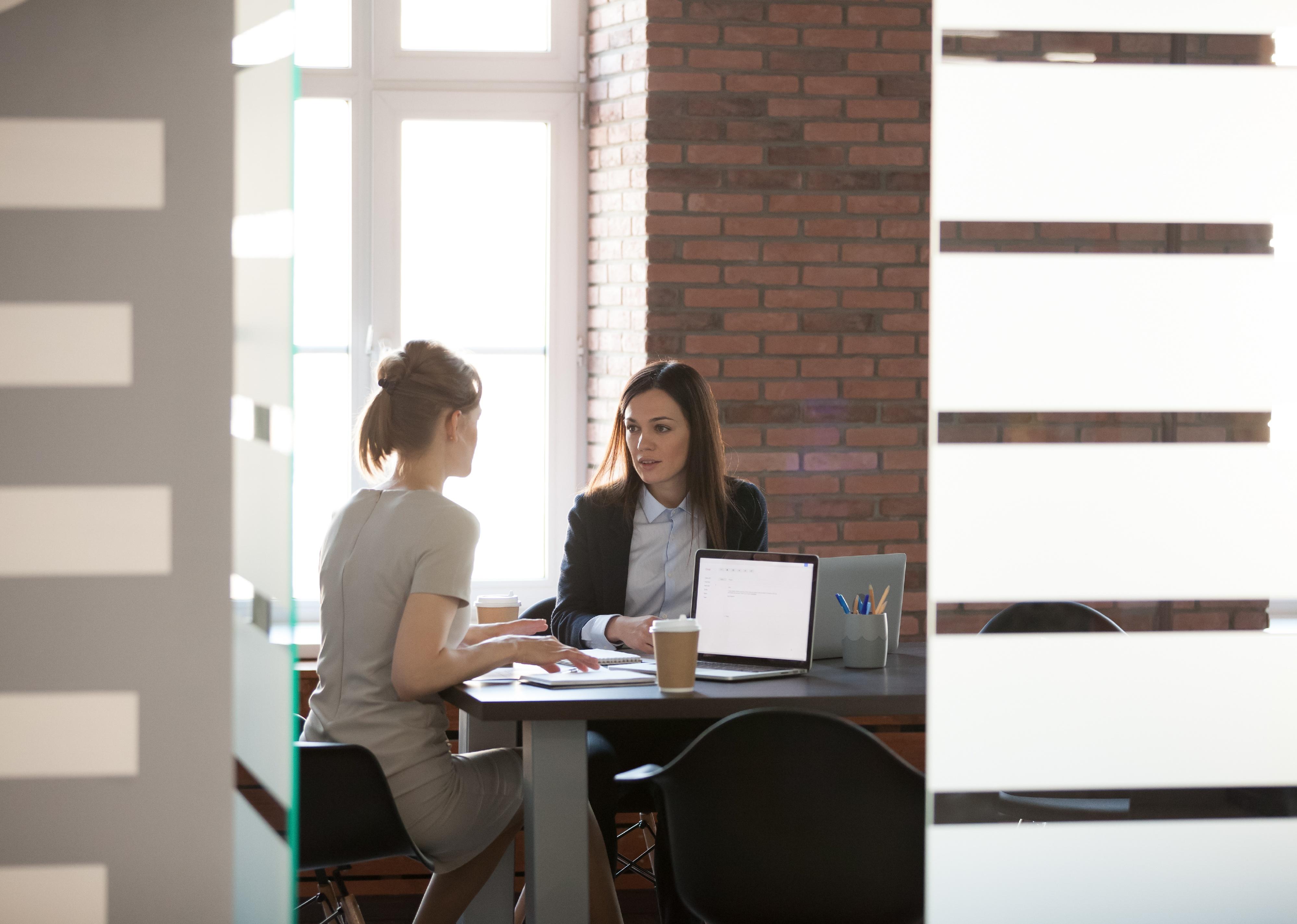 Two businesswomen speaking at a table