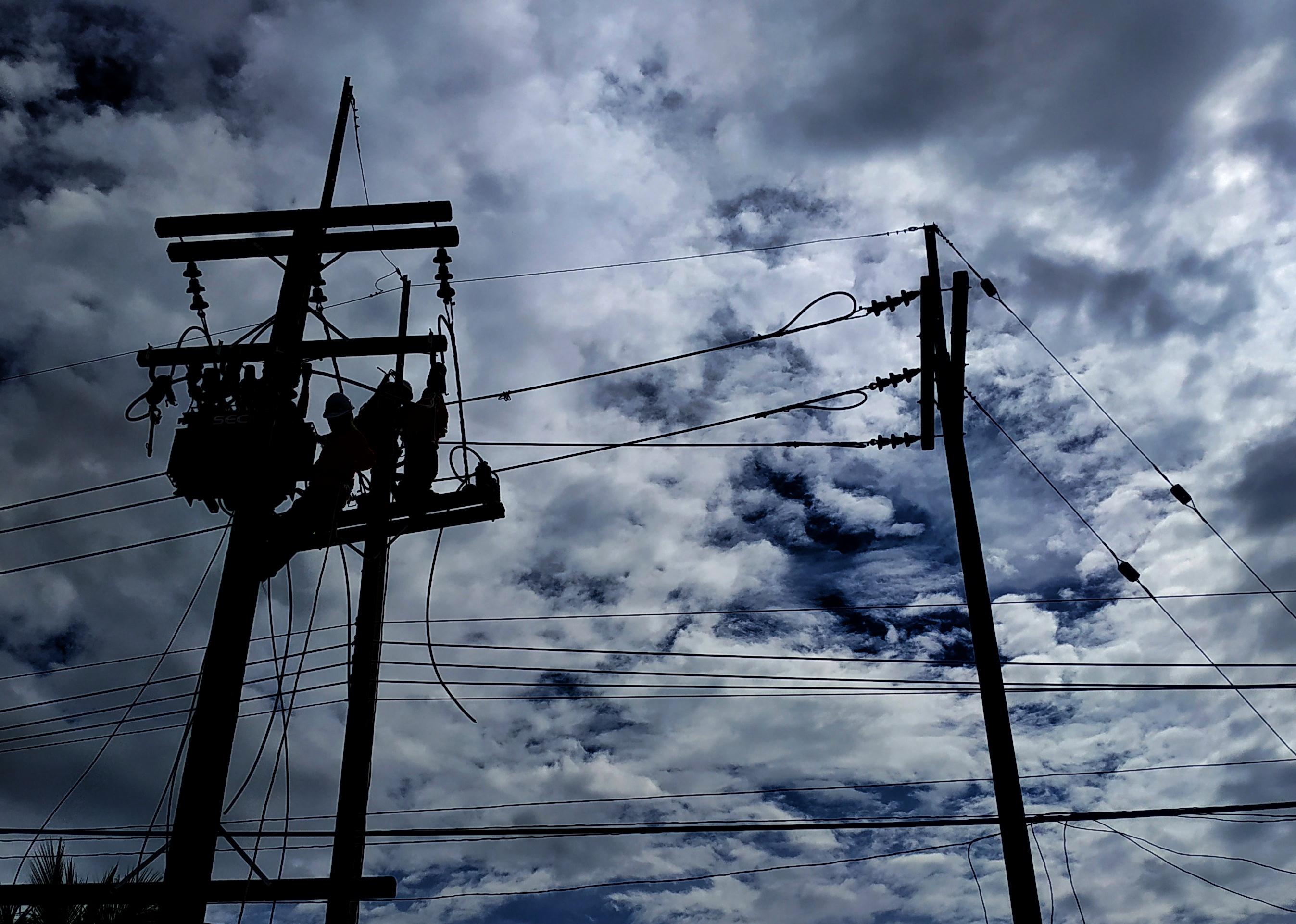 Electrician works on electric poles.