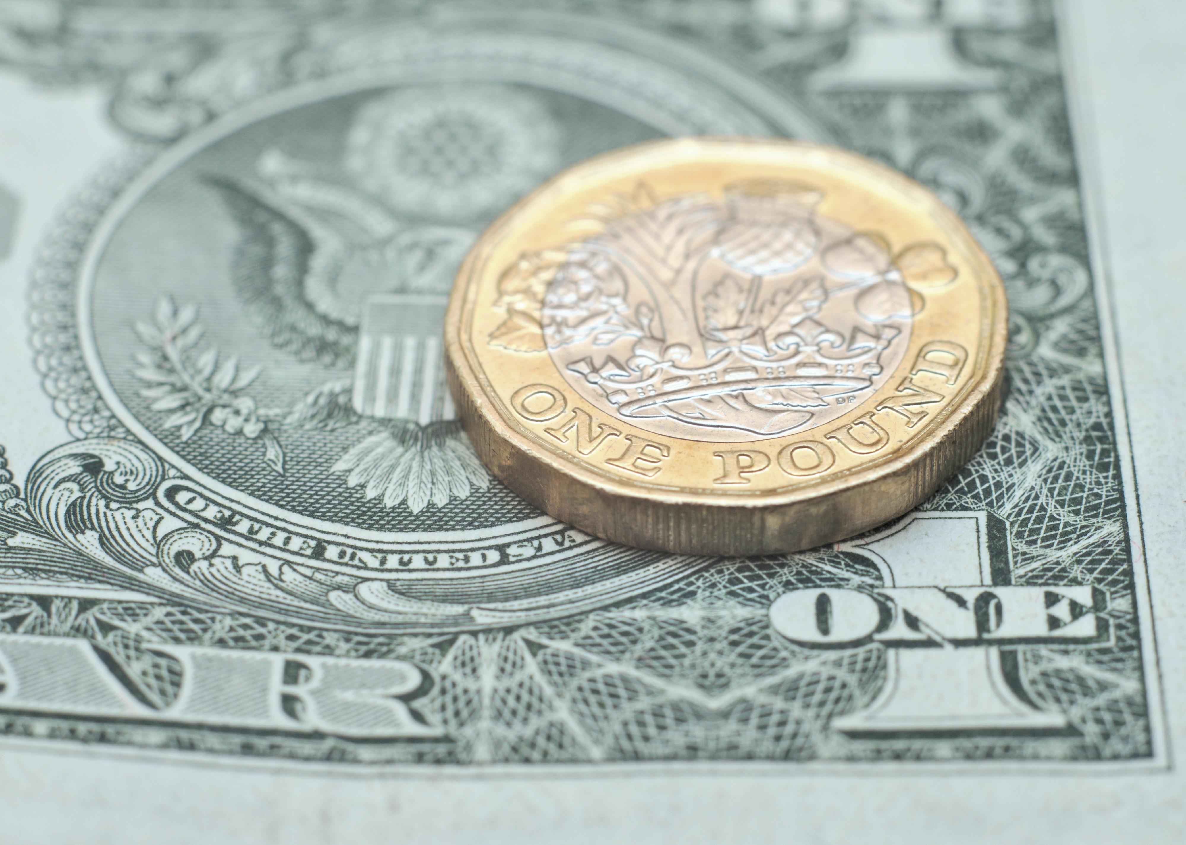 Pound coin sitting on a dollar bill.