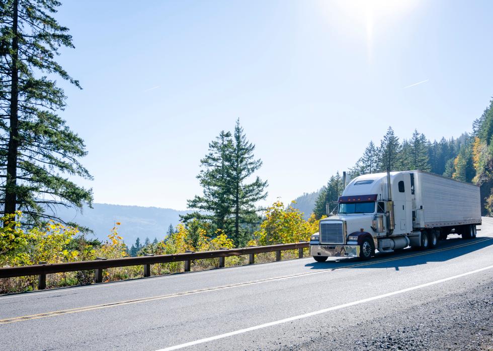 White classic semi truck transporting cargo in refrigerated trailer on a road in Washington