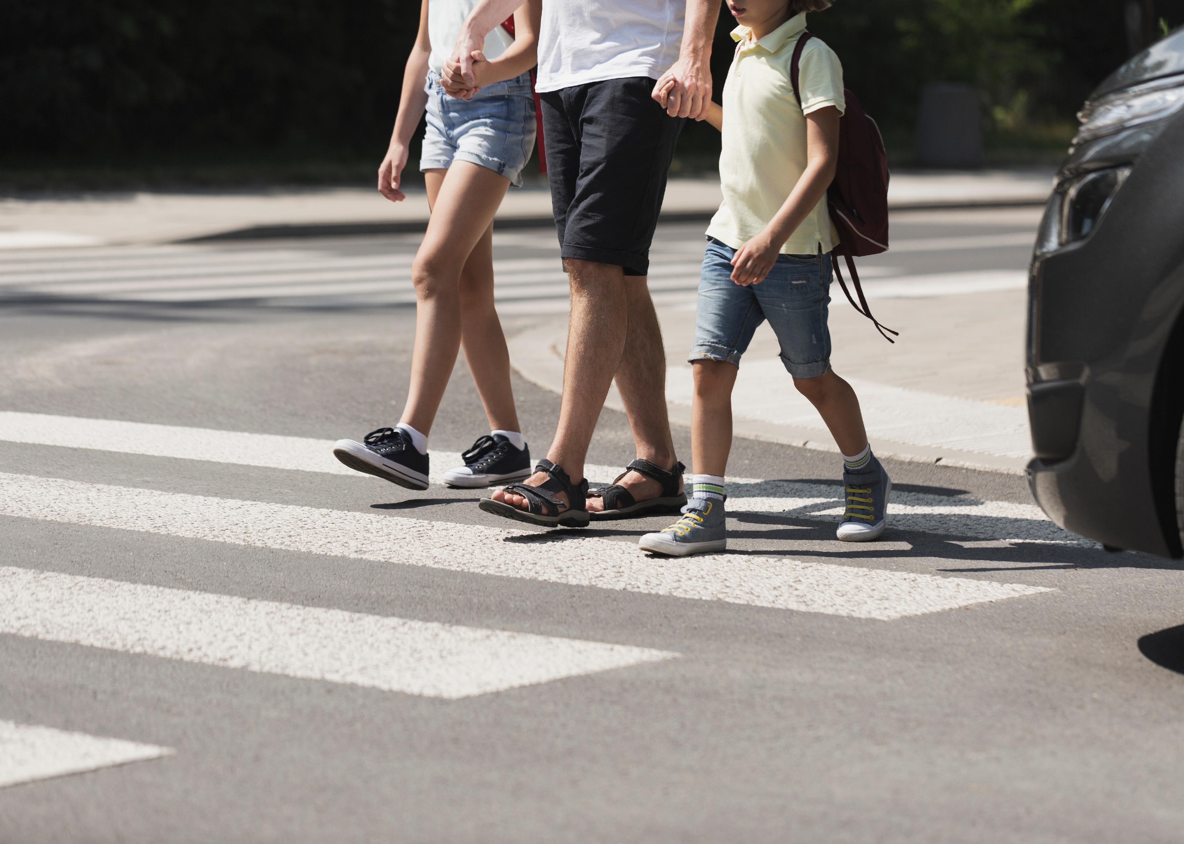 Children crossing the street with their father