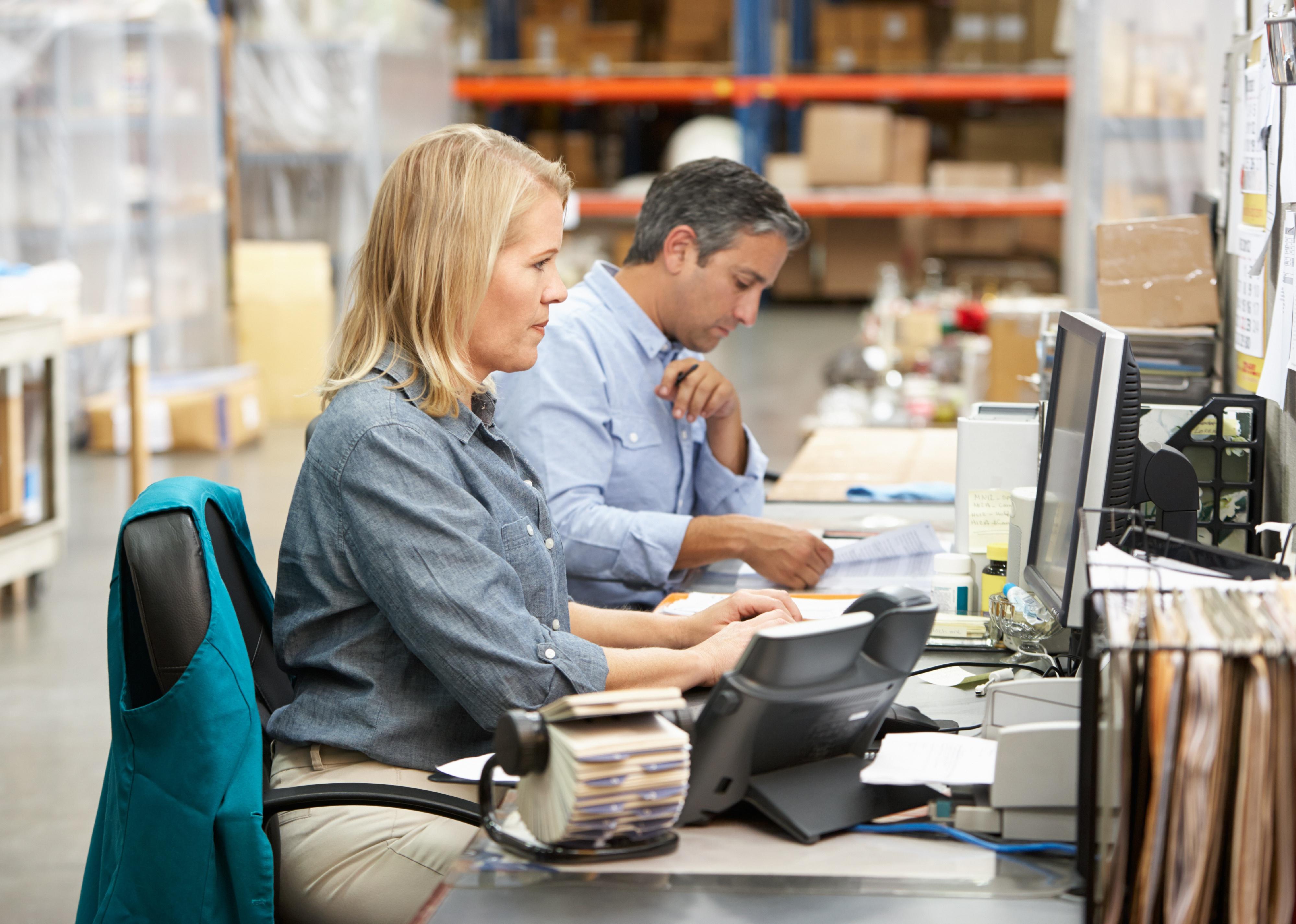 Workers at desks in packing facility.