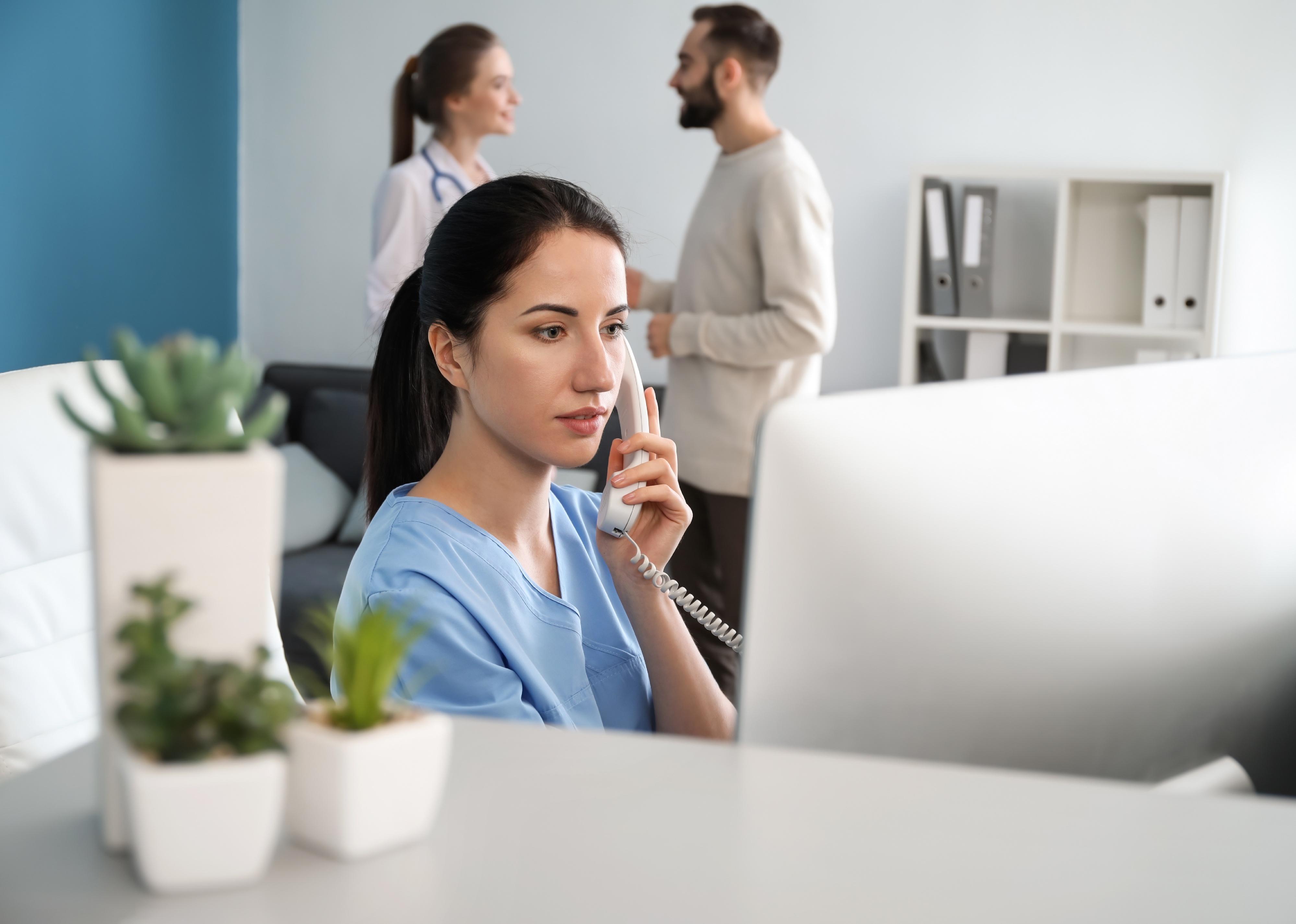 Female receptionist talking by phone in clinic