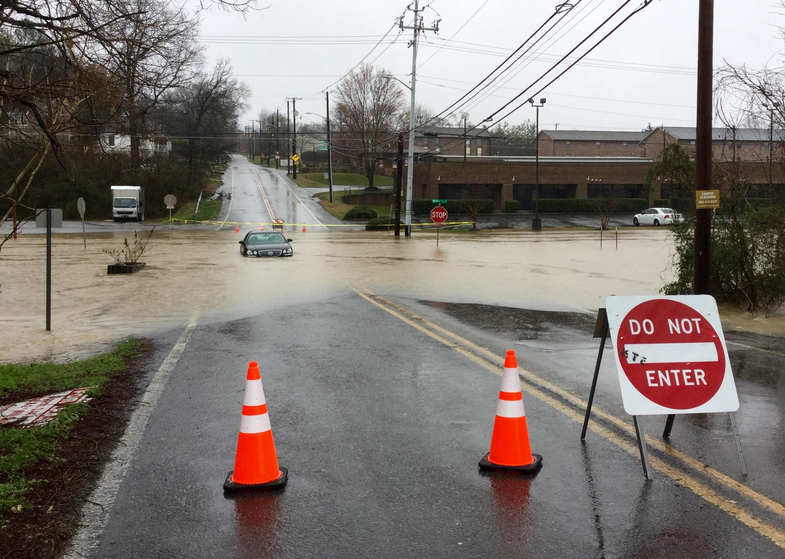 Abandoned car stuck in flooded street.