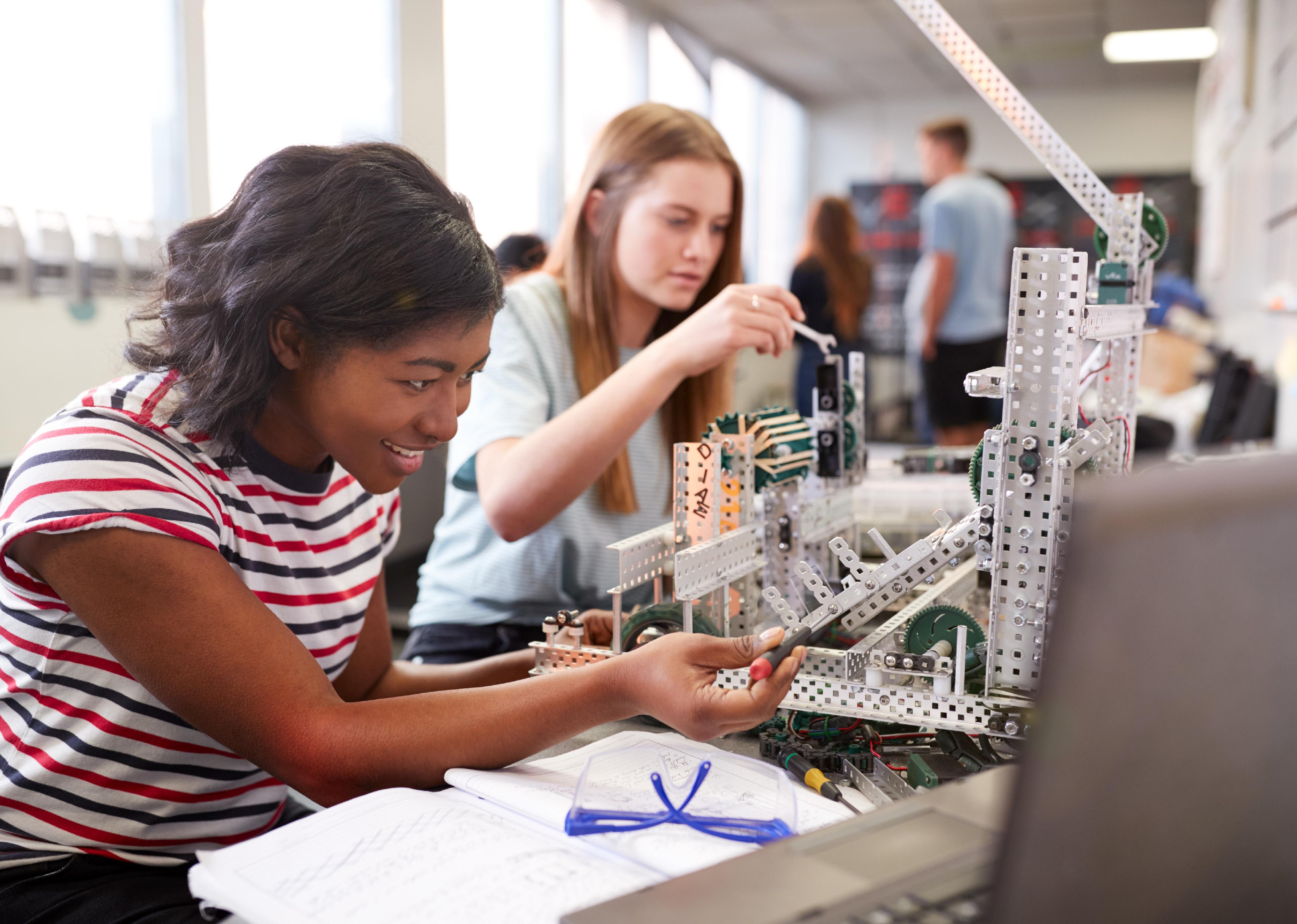 Two college students building a machine in class.
