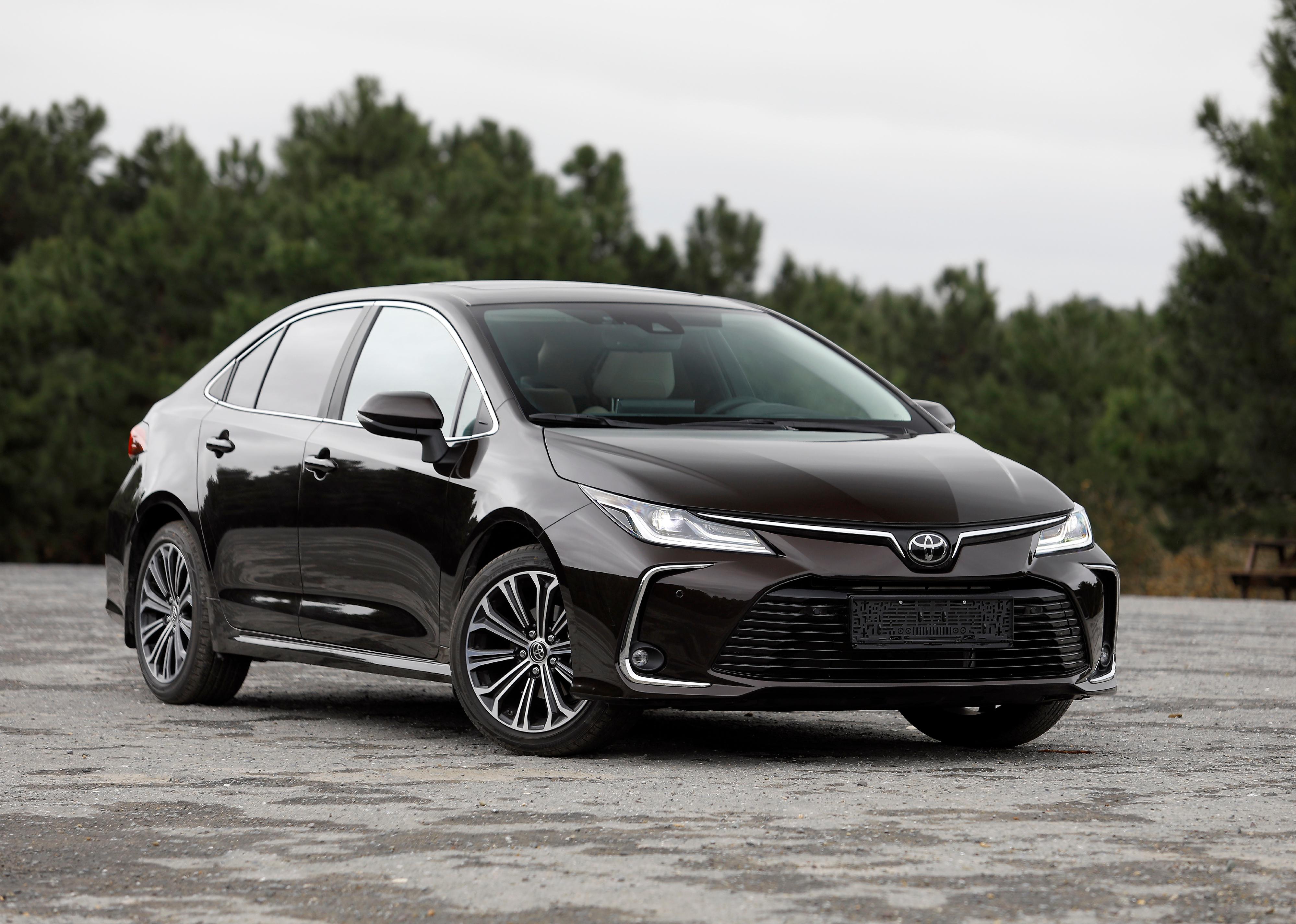 A black Toyota Corolla Sedan on gravel.