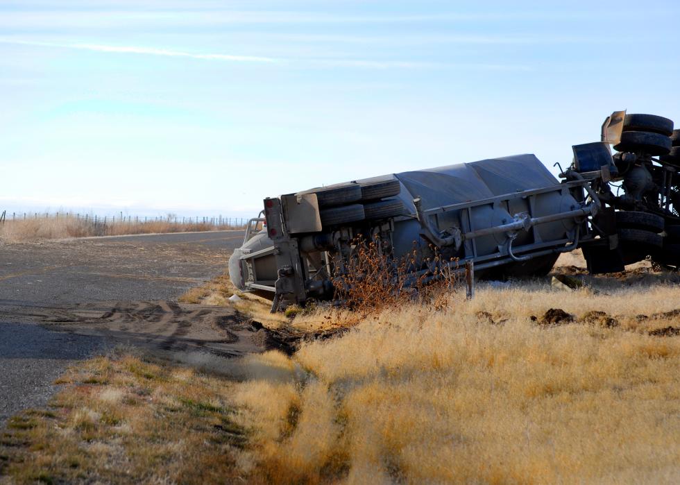 Semi truck trailer rolled over on the side of a road