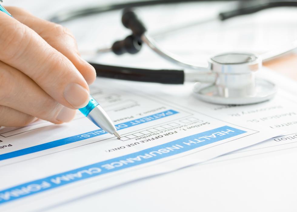 Close-up of a stethoscope and a paper insurance claim being filled out. 