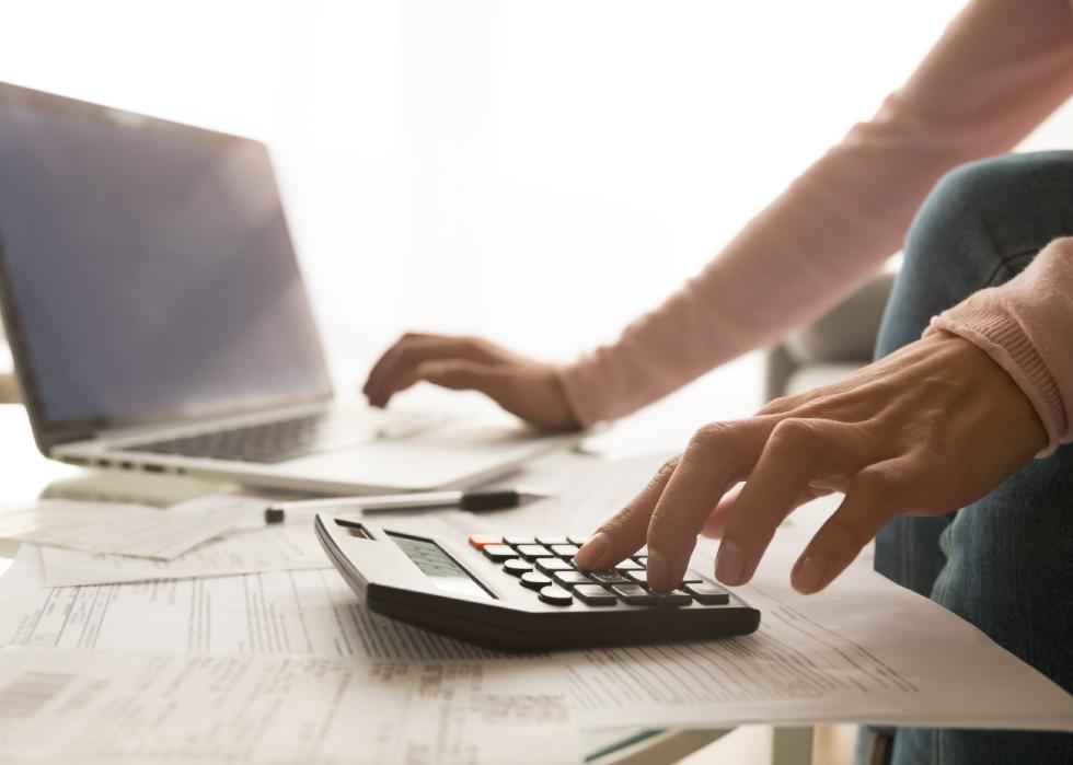 Close-up of woman using laptop and calculator