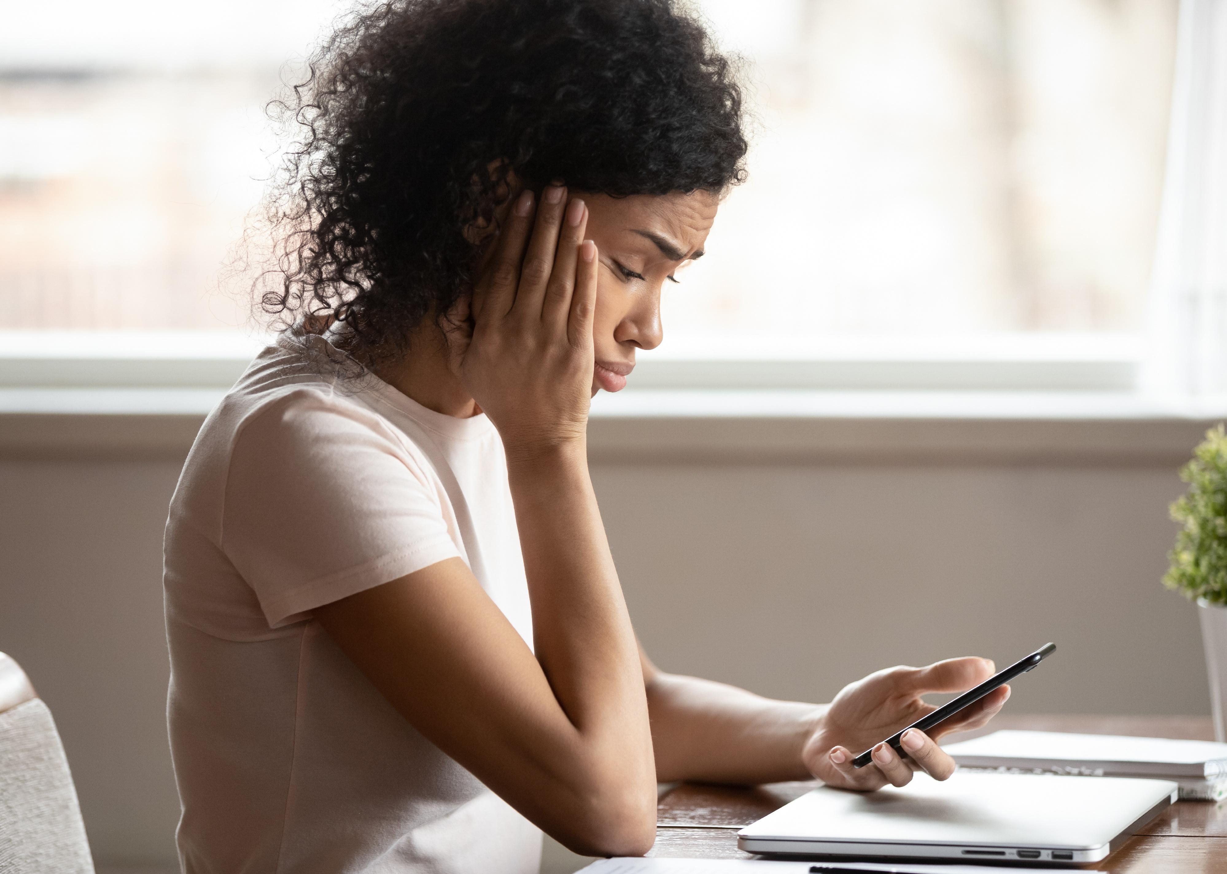 A young woman looking at smartphone frustrated.