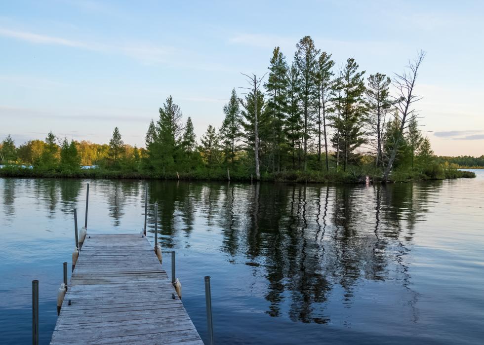 Pier jutting out into reflections of an island in the Chippewa Flowage.